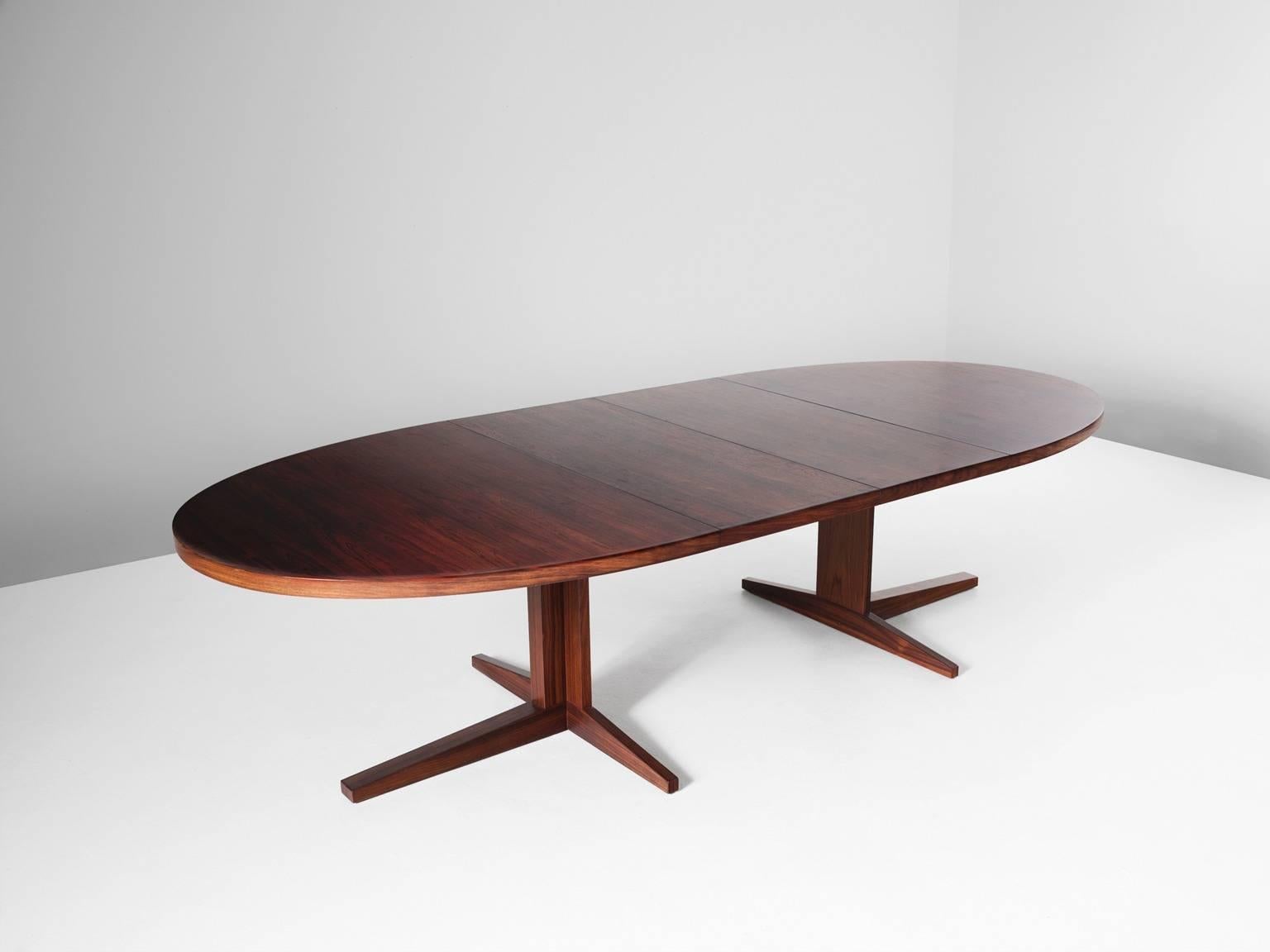 Dining table in rosewood, Scandinavia, 1960s. 

Large oval dining table with two leafs. This table has a very interesting base. In small position the legs form a cross with four points. When extended the table has a base of two legs, each with