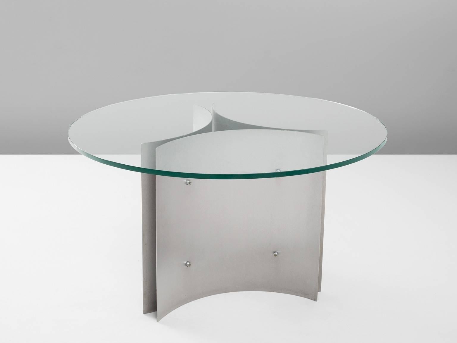 Dining table, in steel and glass, France, 1960s. 

Round pedestal dining table. A circular clear glass top. The base is formed of three concave curved plates of steel, which combine into a triangle or star shape. Due the clear glass top, the