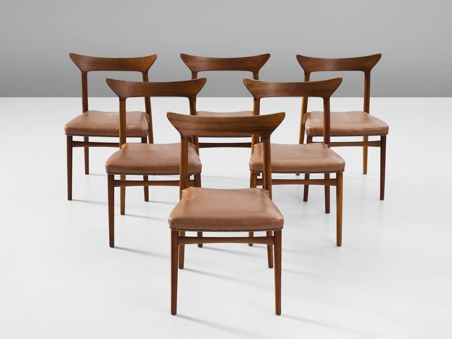 Set of six dining chairs, in walnut and leather, Denmark, 1950s.

This highly rare set of dining chairs shows exquisite Danish craftsmanship. Especially the back is wonderfully sculpted, with slightly upwards directed ends. 
The smooth transition