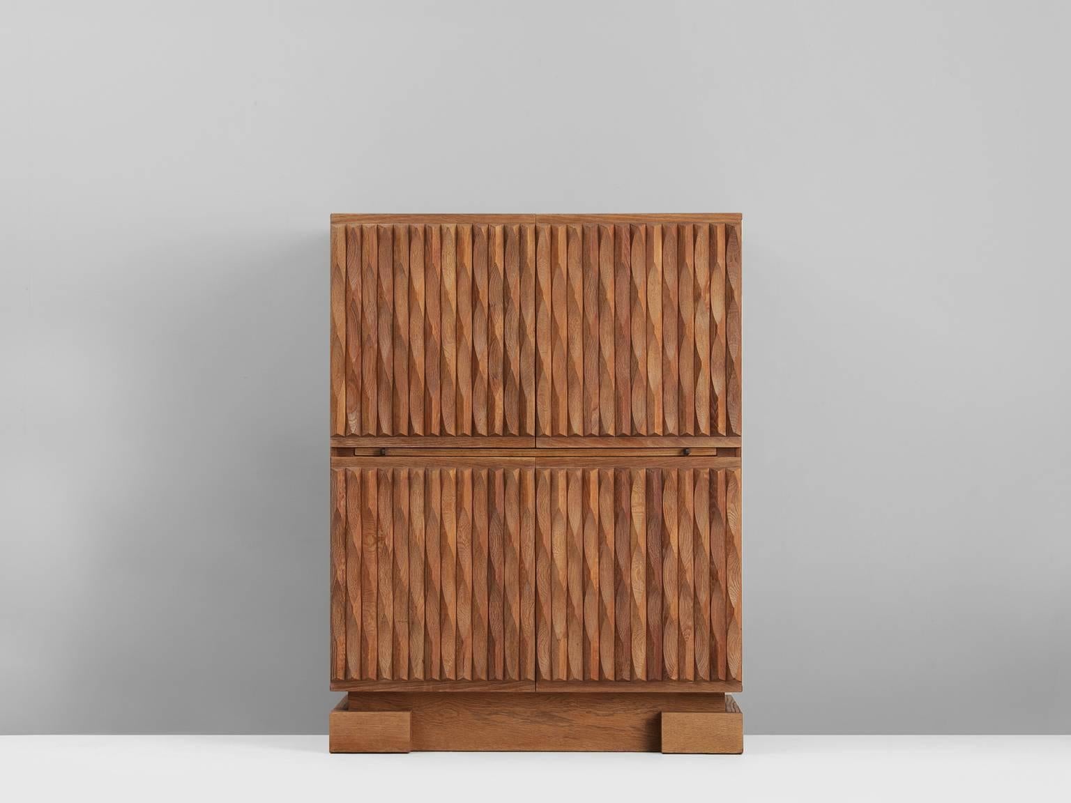 Brutalist credenza, in oak, European, 1970s. 

Sturdy highboard in oak with graphical designed door panels. Four door panels, each with an exceptional three-dimensional pattern. The continuous pattern gives this bar-cabinet a very strong