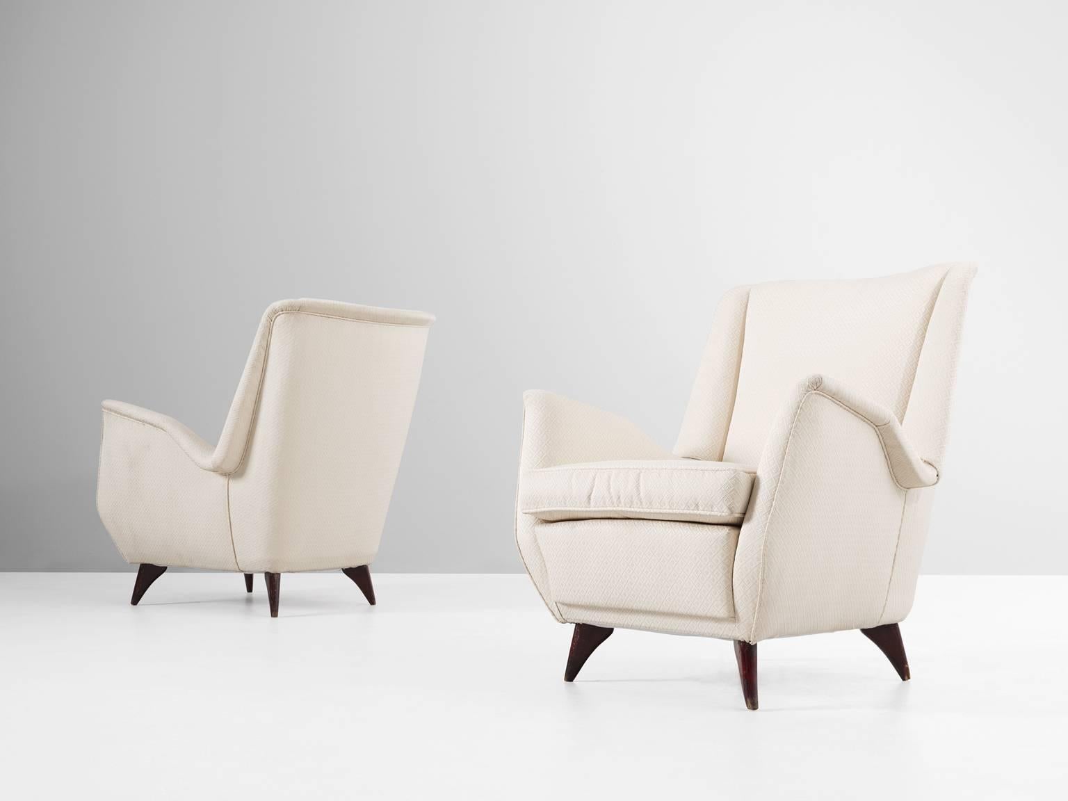 Set of two lounge chairs, in wood and fabric, Italy, 1950s.

Two Italian armchairs in off-white pattern fabric. These chairs show beautiful and elegant lines. The wide seating is accomplished with nicely folded armrests. The dark stained wooden