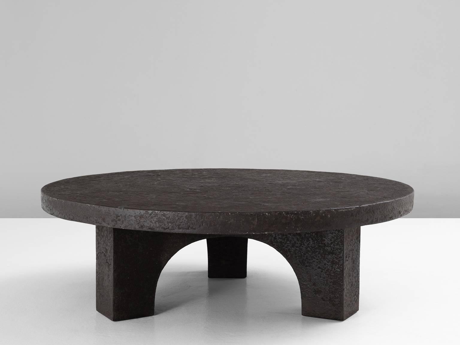 Cocktail table in stone, Europe, 1970s. 

Round coffee table in stone. This table has an interesting appearance, the grey stone looks like cast iron. The round top is supported by three legs, which shows nice lines and are formed into arches.