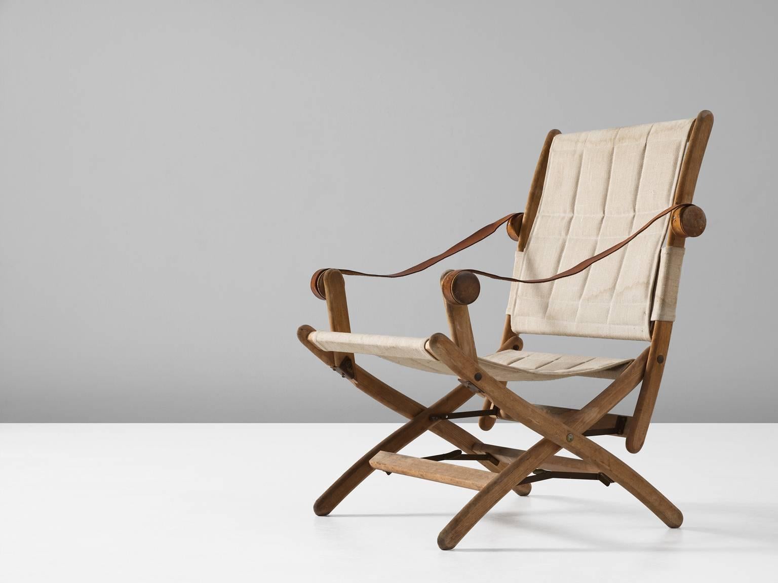 Folding chair in beech, leather and canvas, Scandinavia, 1950s.

Interesting safari chair with beautiful cognac leather armrests. The wooden frame in beech shows nice details, so as the knobs for the armrests. The legs are X-shaped with