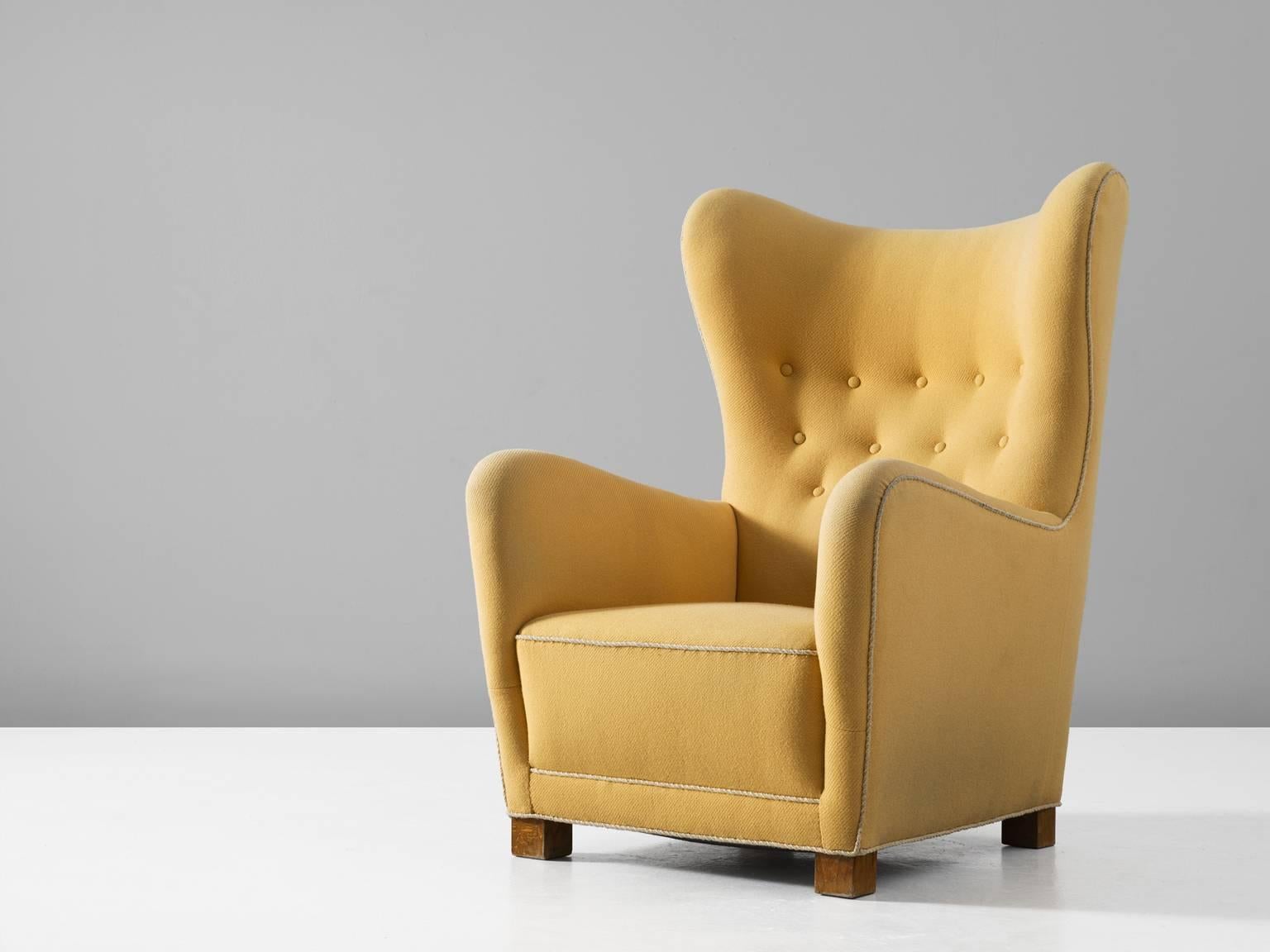 Wingback chair, in oak and fabric, for Fritz Hansen, Denmark, circa 1945.

Classical high back chair, with beautiful tufted back. Inspired on a traditional wingback chair, yet minimized to a Scandinavian Modern design. This lounge chairs shows