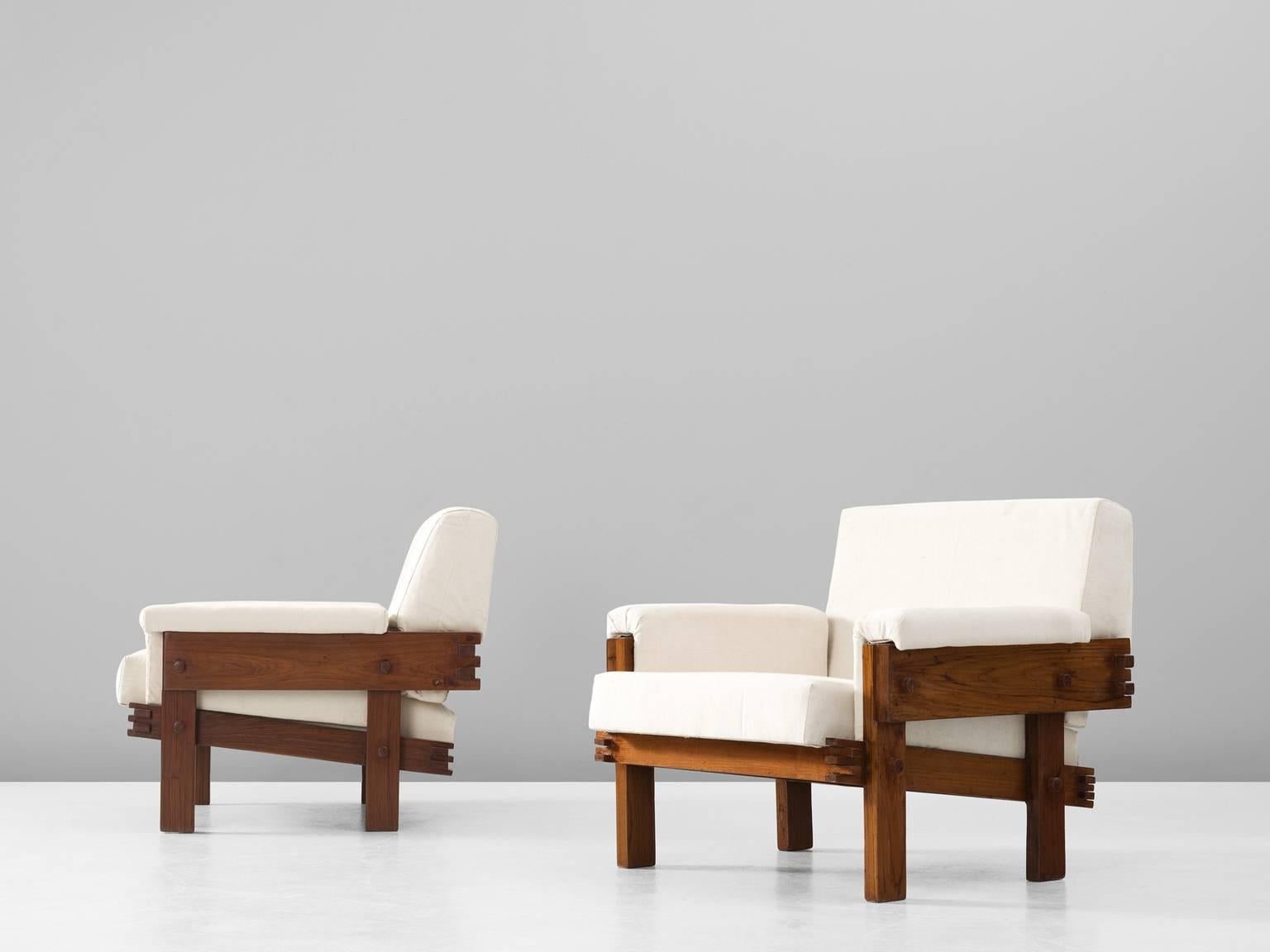 Pair of lounge chairs, in teak and fabric, Brazil, 1960s. 

Beautiful pair of cubic easy chairs in dark stained teak with off-white fabric upholstery. These chairs have a sturdy design, in which the wood-joints and structure of the wood are the