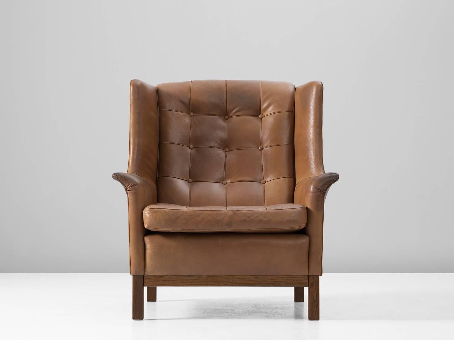 High back chair, in leather and wood, by Arne Norell, Sweden, 1960s. 

Wonderful comfortable cognac buffalo leather easy chair by Swedish designer Arne Norell. This lounge chair comes with a very high standard of comfort, as where Norell is known