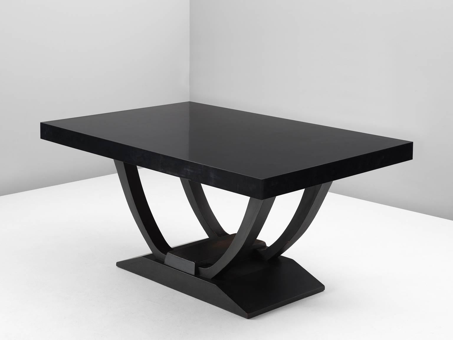 Dining table, in oak and walnut, Europe, 1930s. 

Art Deco center table with beautiful sculptural base. This ebonized table has a square base with sloping sides. The legs are two arch shaped curves. The table's top is rectangular and made of black