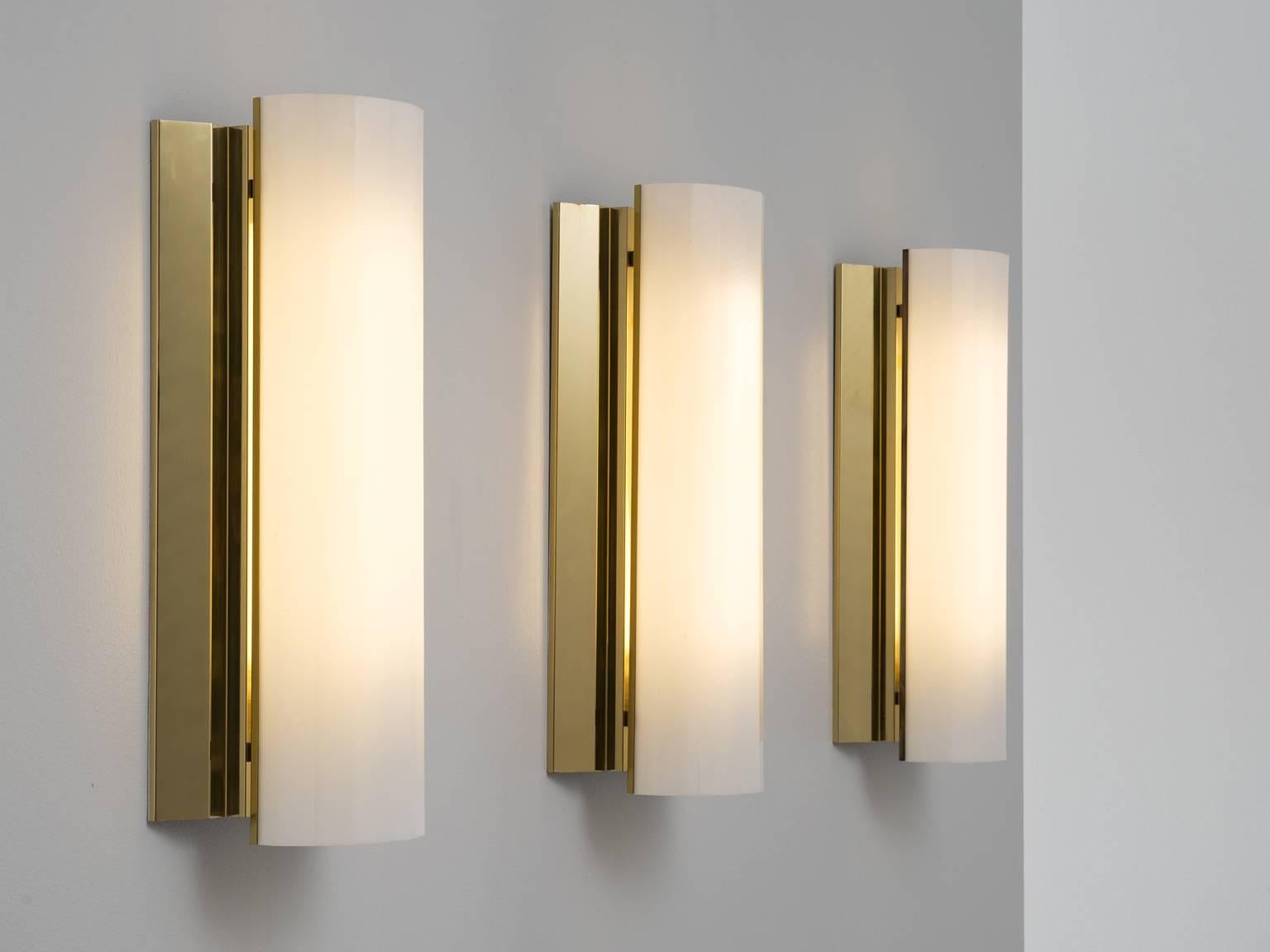 Set of three large wall lights, in brass and plastic, Sweden, 1970s. 

Set of six large wall lights. Each light consist of a large brass holder with a polygon shaped white Lucite shade. Due the combination of materials these wall lights will create