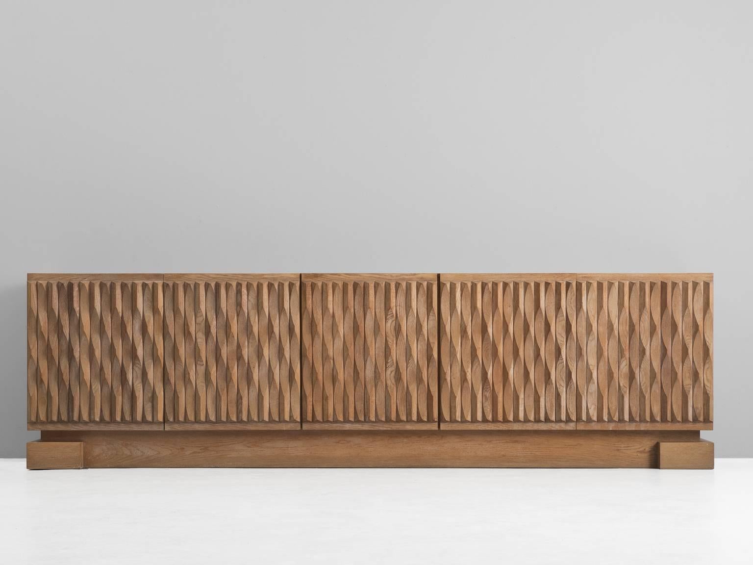 Sideboard, in oak, Europe, 1970s.

Credenza with graphical door panels in blond oak. Five-door panels, each with an exceptional three-dimensional pattern. The continuous pattern gives this cabinet a very strong expression, emphasized by its base.