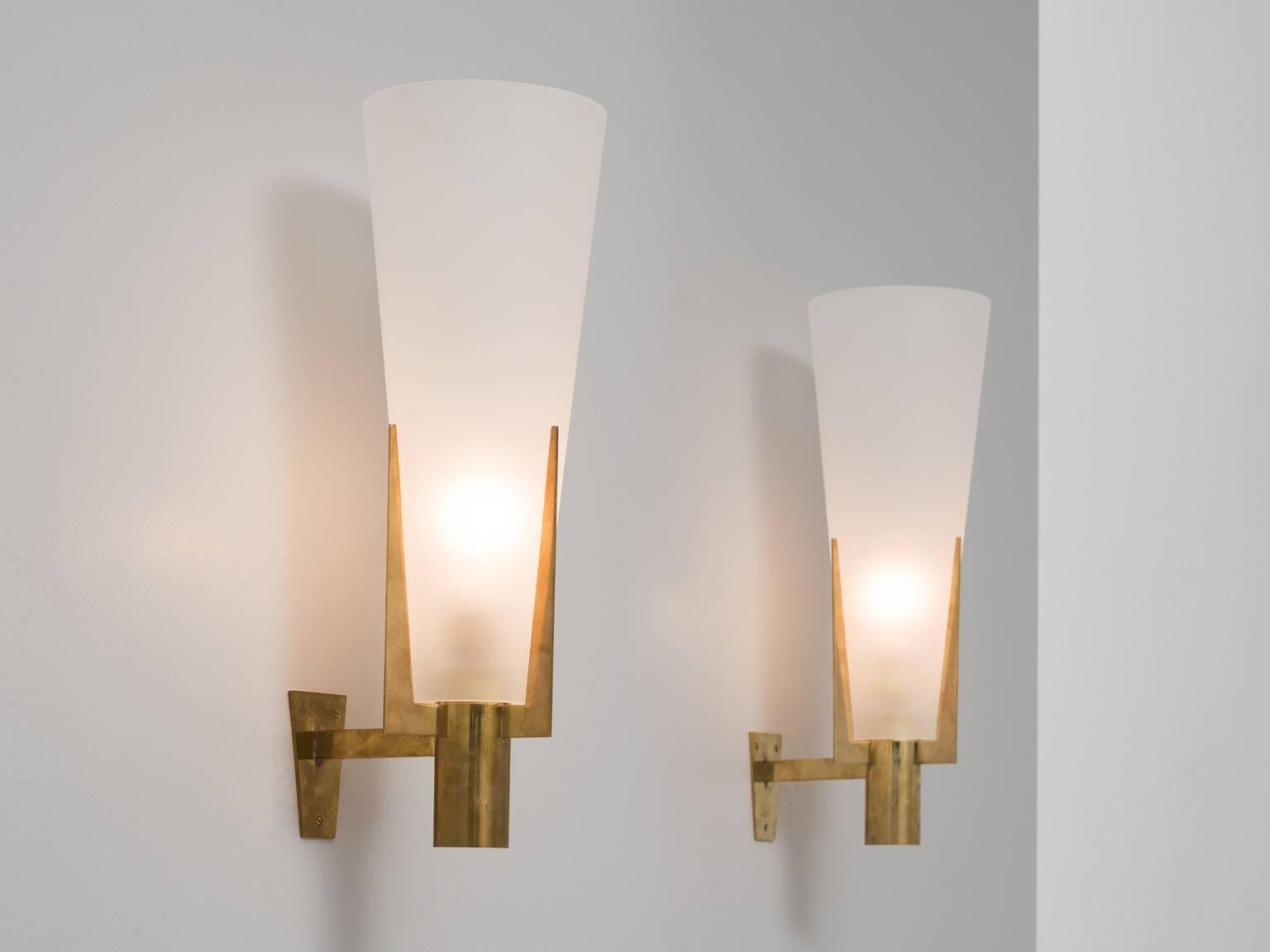 Pair of wall lights in brass and glass, Europe, 1970s.

Set of two large wall lights in brass and frosted glass. These sconces hold a beautiful brass frame with an admirable patina. Three 'pins' hold the large opal conical shade. Due the large