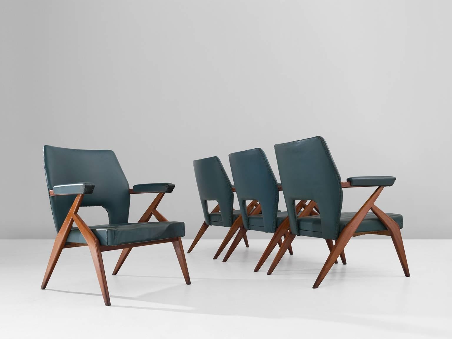 Set of four armchairs, in mahogany and faux-leather, Italy, 1960s.

Quartet of four mahogany armchairs with petrol blue leatherette upholstery. These wide armchairs have a refined design with Italian elegance. The wooden frame shows beautiful