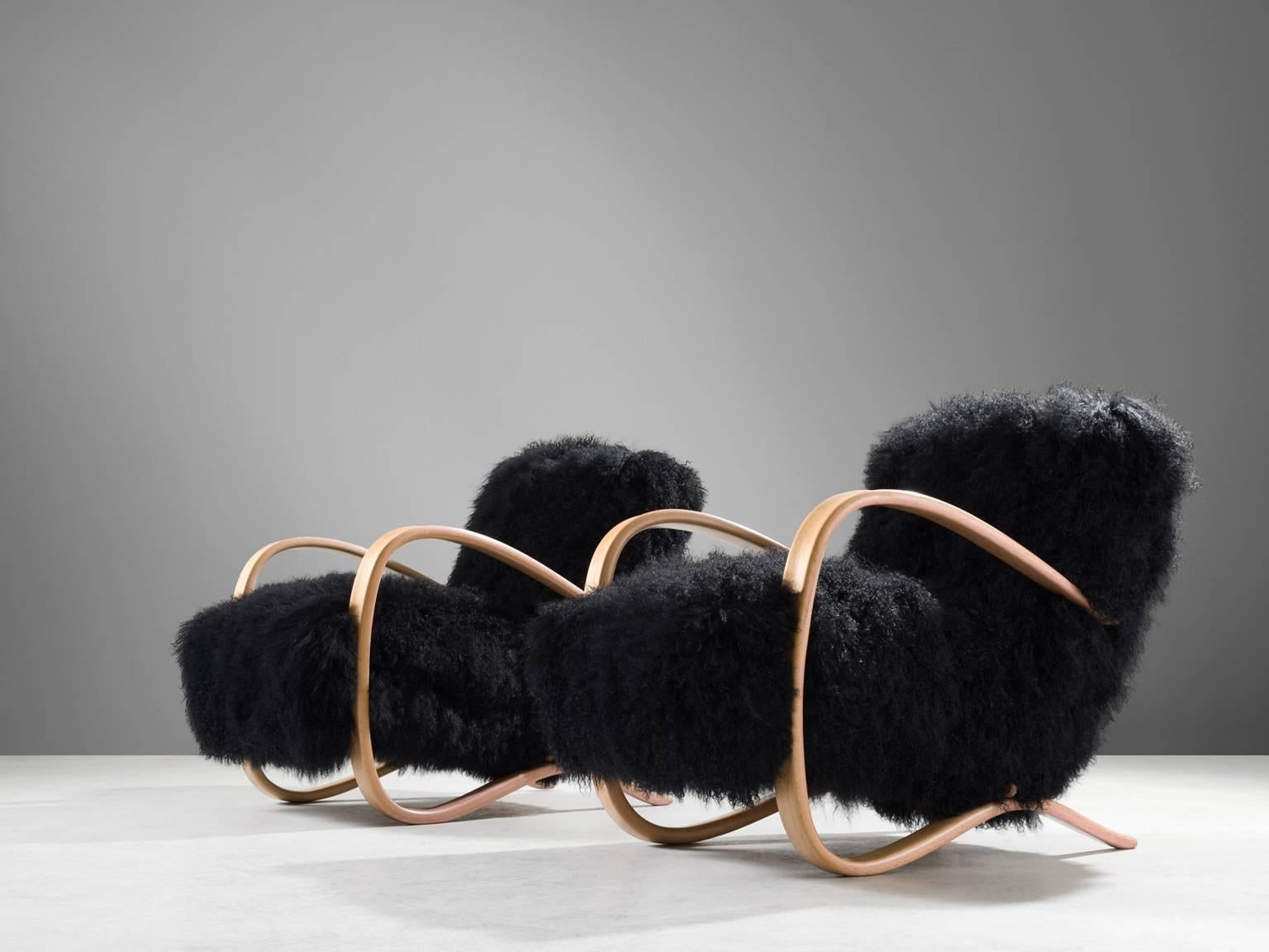 Pair of lounge chairs, in beech and sheepskin, by Jindrich Halabala, Czech Republic, 1930s.

Extraordinary pair of easy chairs with black Tibetan lambswool upholstery. These chairs have a very dynamic appearance. This fuzzy upholstery gives these