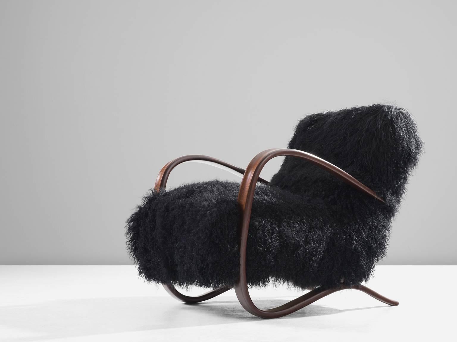 Lounge chair, in beech and sheepskin, by Jindrich Halabala, Czech Republic 1930s.

Extraordinary easy chair with black Tibetan lambswool upholstery. This lounge chair has a very dynamic appearance. The fuzzy upholstery gives this armchair a very