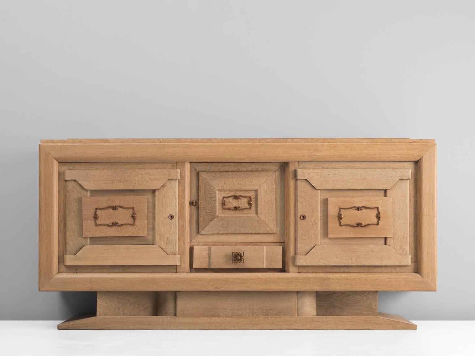 Cabinet, in oak and brass, by Charles Dudouyt, France, 1930s. 

French Art Deco oak credenza designed by the decorator Charles Dudouyt. The solid wooden frame gives this sideboard a sturdy character. The door panels show an interesting pattern of