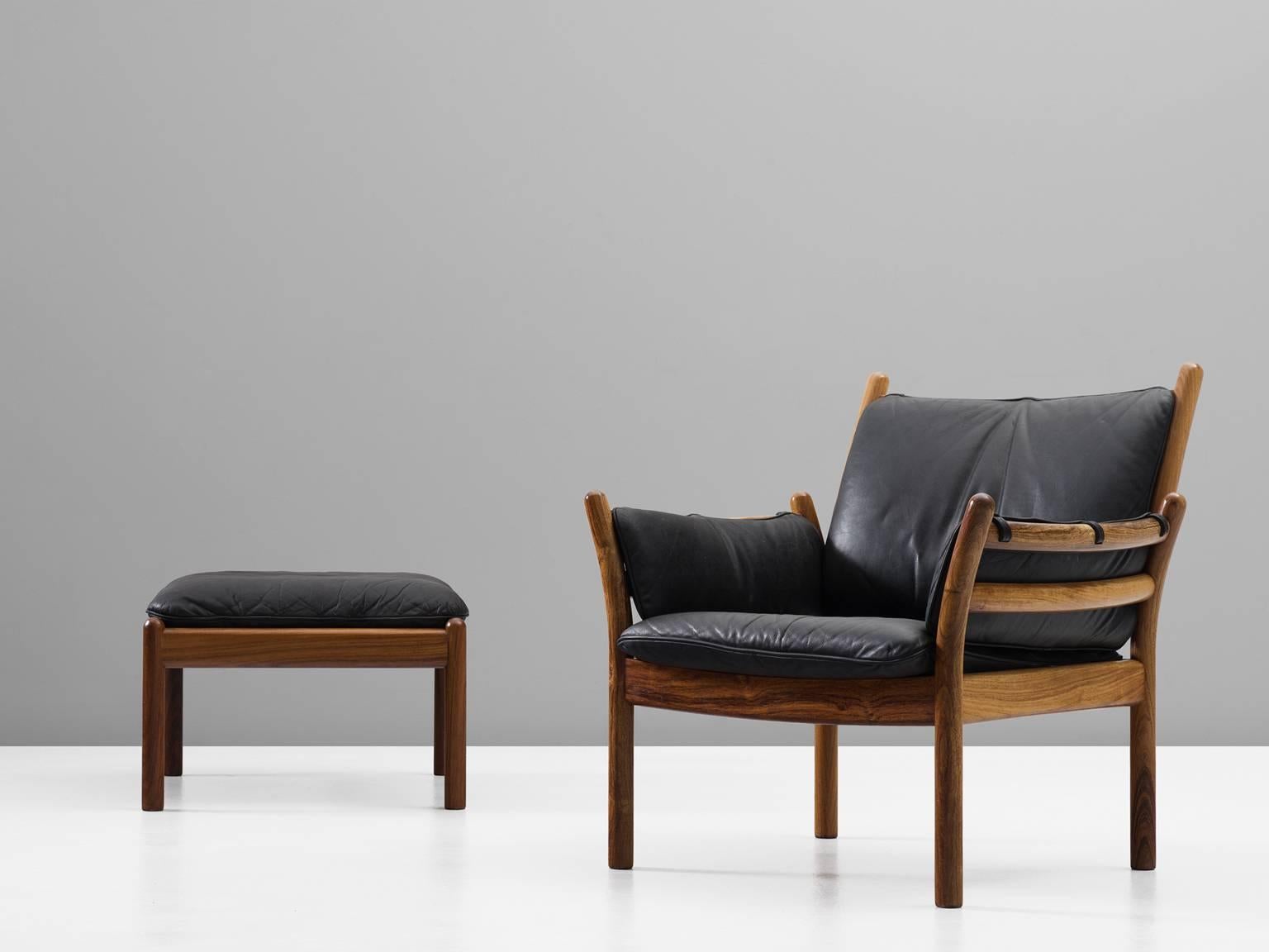 Easy chair and ottoman, in rosewood and leather by Illum Wikkelsø for CFC Silkeborg, Denmark, 1960s. 

Elegant lounge chair and ottoman in solid rosewood and black leather upholstery. This chair has a beautiful open character. The cylindrical