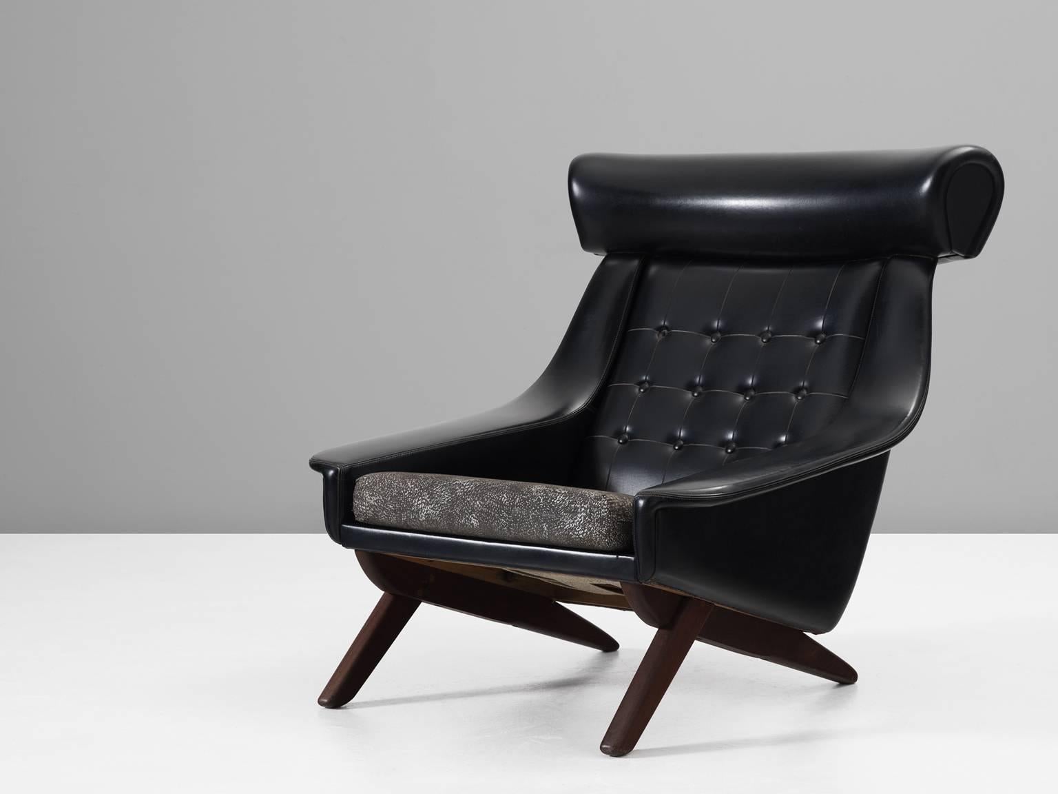 Lounge chair, in faux-leather, fabric and wood, Denmark 1960s. 

Rare easy chair in black leatherette upholstery. This 'Ox Chair' shows some interesting details. Like the wide and large headrest at the top of the back. The buttons on the back