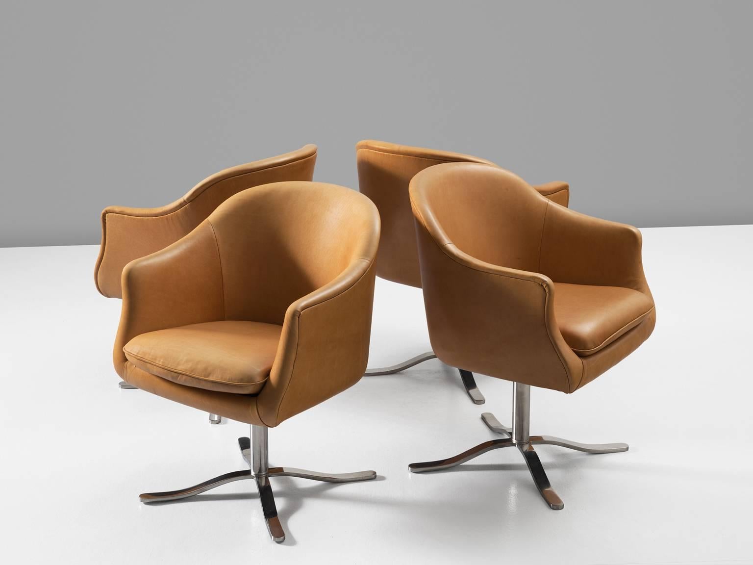 Set of four swivel chairs in metal and leather, 1960s. 

Four cognac leather conference chairs. Very comfortable swivel desk chairs in natural cognac leather. The base consists of four curved chrome legs. The legs nicely follow the smooth lines of