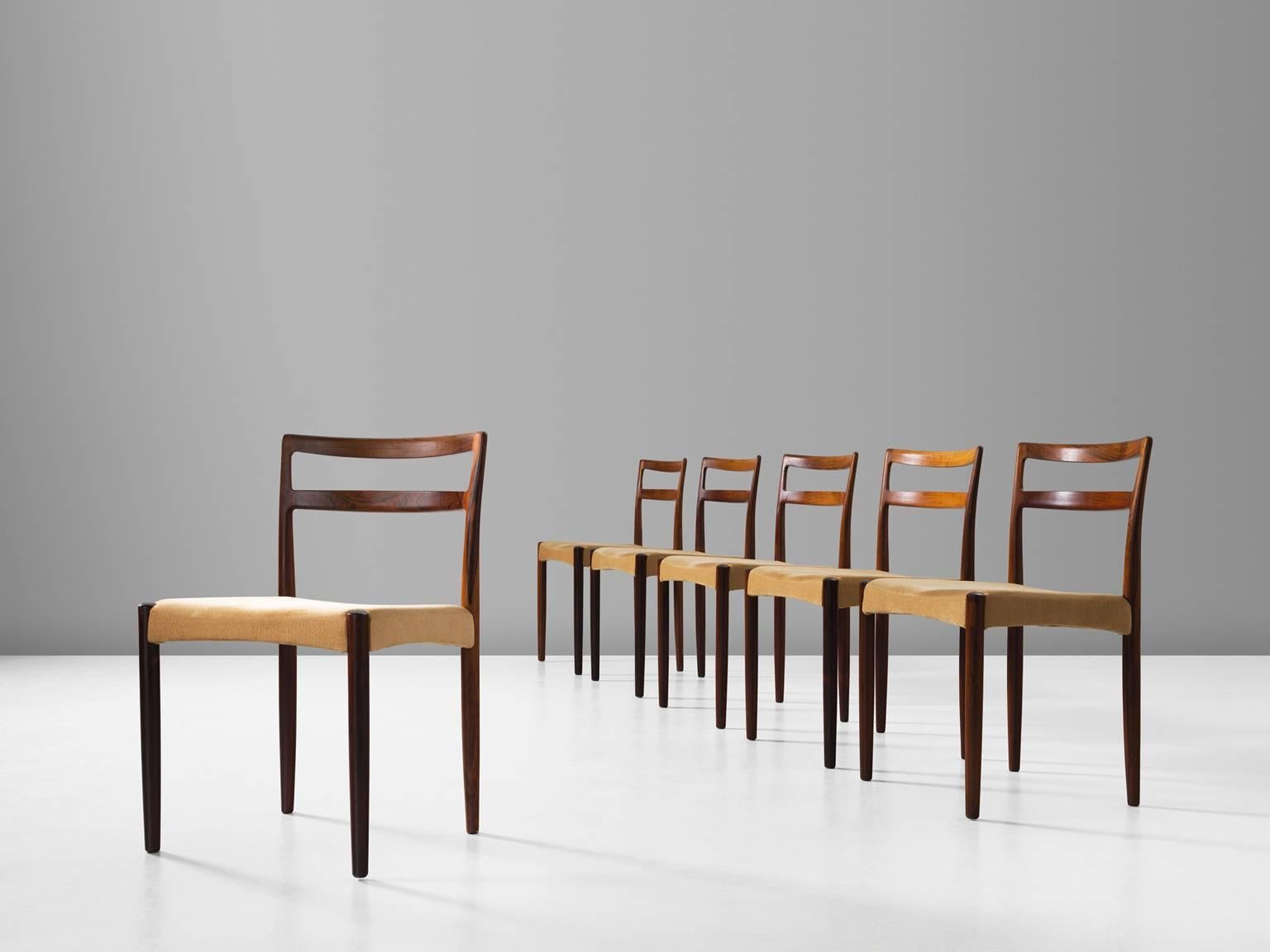 Set of six dining chairs, in rosewood and fabric, by Harry Ostergaard for Randers Møbelfabrik, Denmark, 1961.

Set of six dining chairs in rosewood with fabric upholstery. The basic and linear character of the wooden frame gives these chairs some