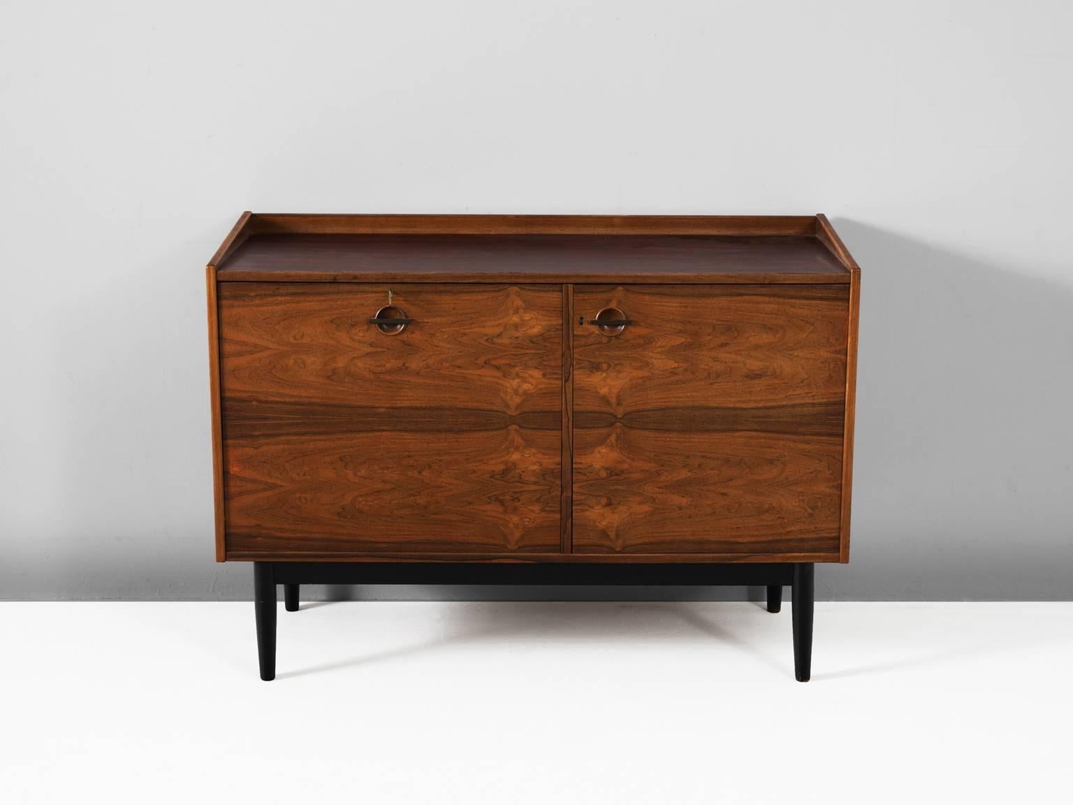 Bar cabinet, in rosewood and metal, by Hans Olsen for Brande Mobler, Denmark, 1960s.

A unique piece by designer Hans Olsen. This looks like a beautiful small sideboard, but once open versatile storage facilities will appear. The left side gives