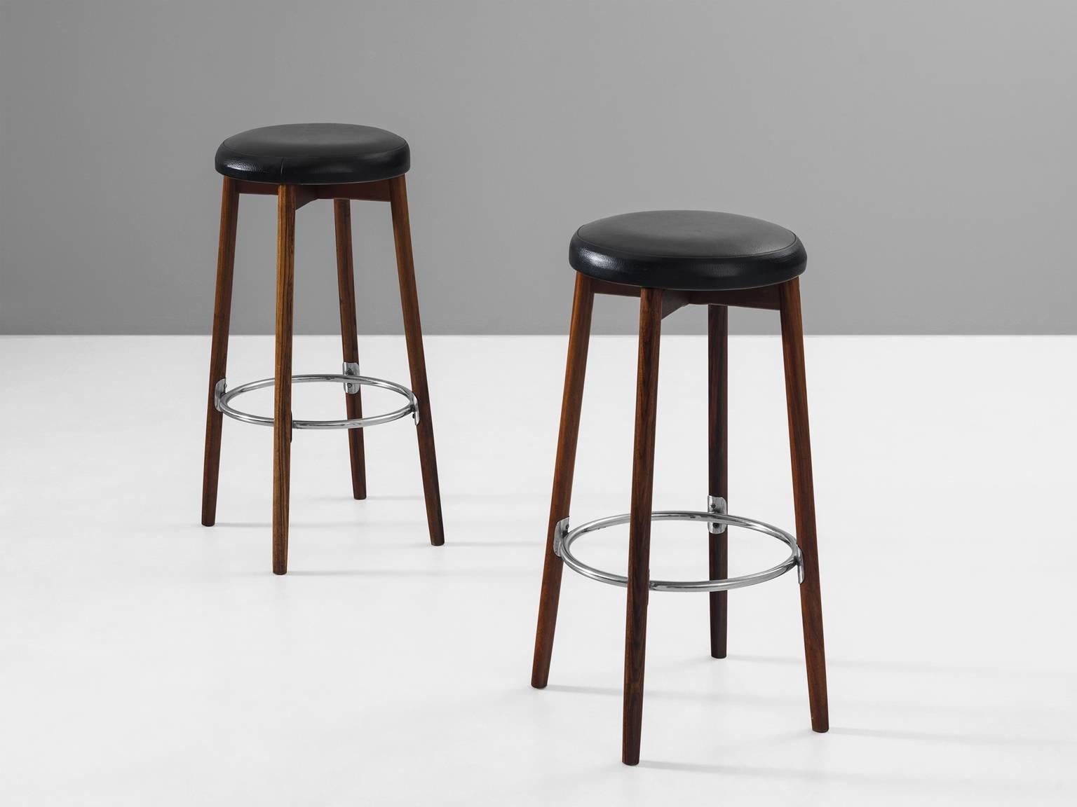 Barstools, leather metal and rosewood, 1970s, Europe.

This strong set of two bar stools is very solid in appearance. The metal ring that connects the four mahogany legs is perfectly mirrored in the black leather seat. The wood that serves as a base