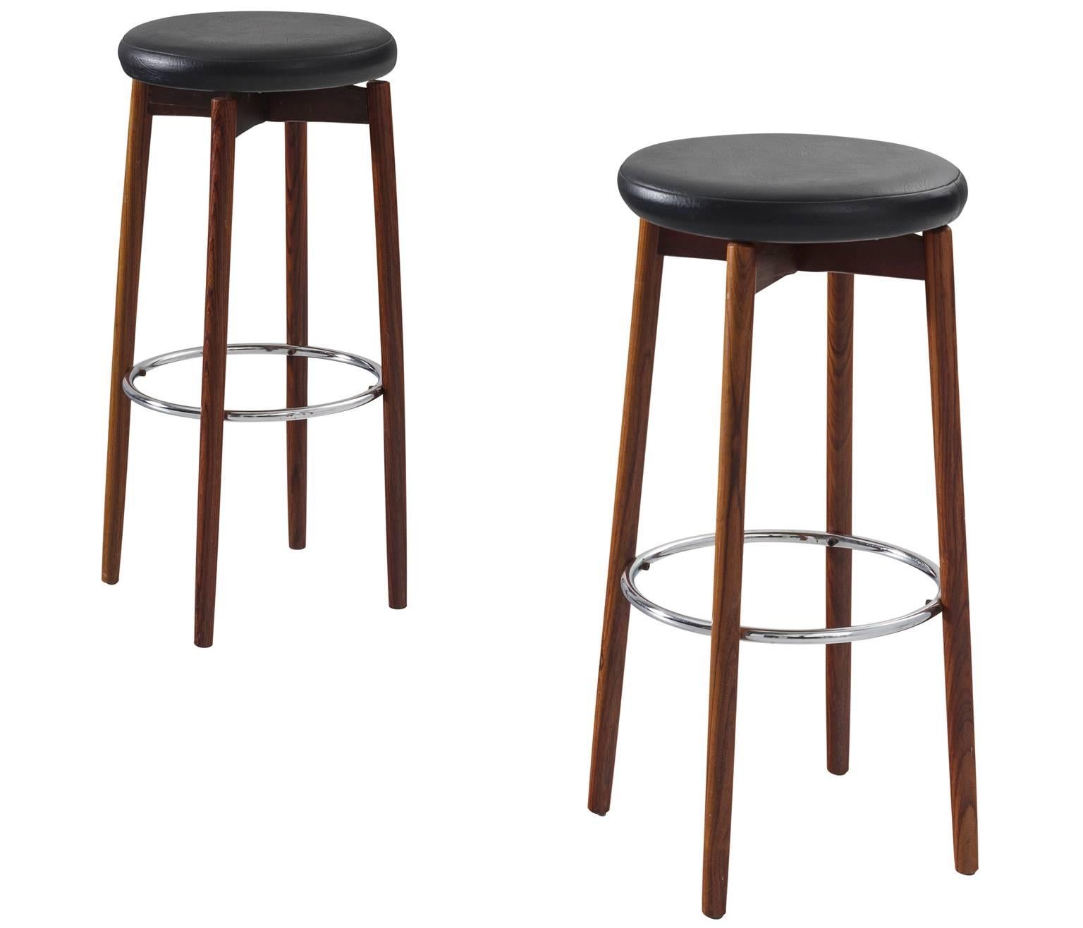 Barstools, leather metal and rosewood, 1970s, Europe.

This strong set of two bar stools is very solid in appearance. The metal ring that connects the four mahogany legs is perfectly mirrored in the black leather seat. The wood that serves as a