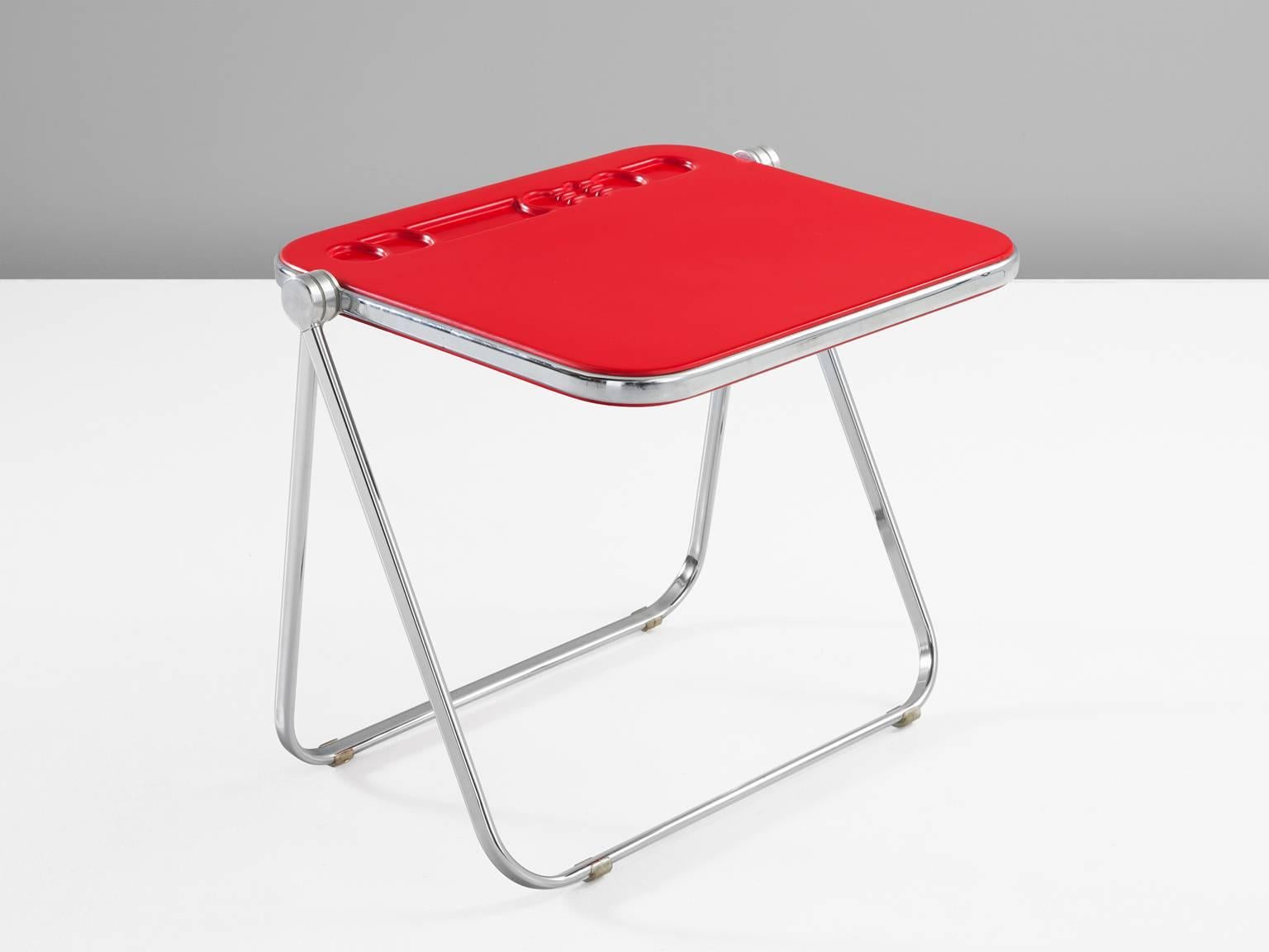 Folding desk, Red ABS plastic and chromed steel, 1970s, Italy. 

This playful item is designed by Giancarlo Piretti for Castelli. The vibrant red top is a perfect match with the bold design of this little table. The desk could function perfectly