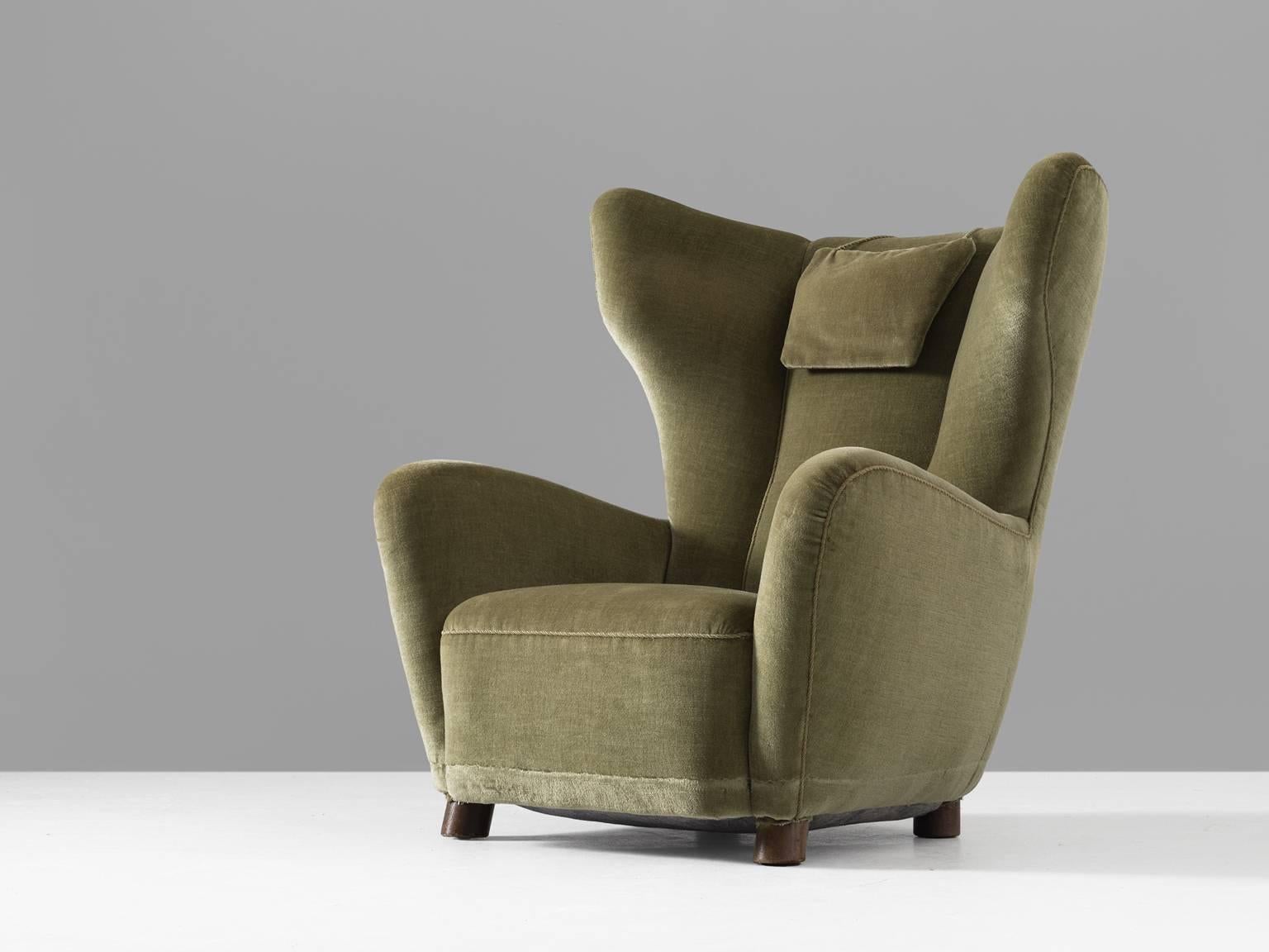 Danish lounge chair, green velvet, 1950s.

This extraordinary wing back chair is from Danish origin. The chair embraces the sitter thanks to its sculpted corners and arm rests. The legs of the chair are made from wood. This chair has the style of