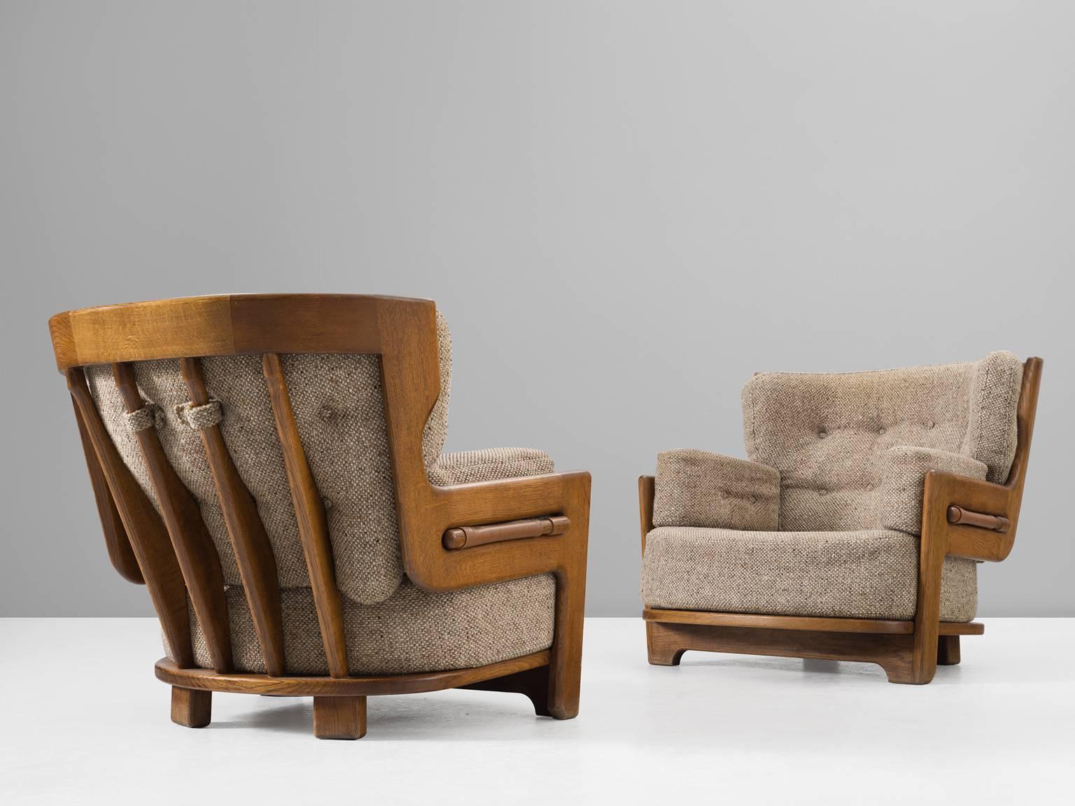 Guillerme et Chambron, set of two lounge chairs, in oak and fabric, France, 1960s. 

Set of two extraordinary Guillerme and Chambron armchairs, in solid oak with the typical characteristic decorative details at the back and capricious forms of the