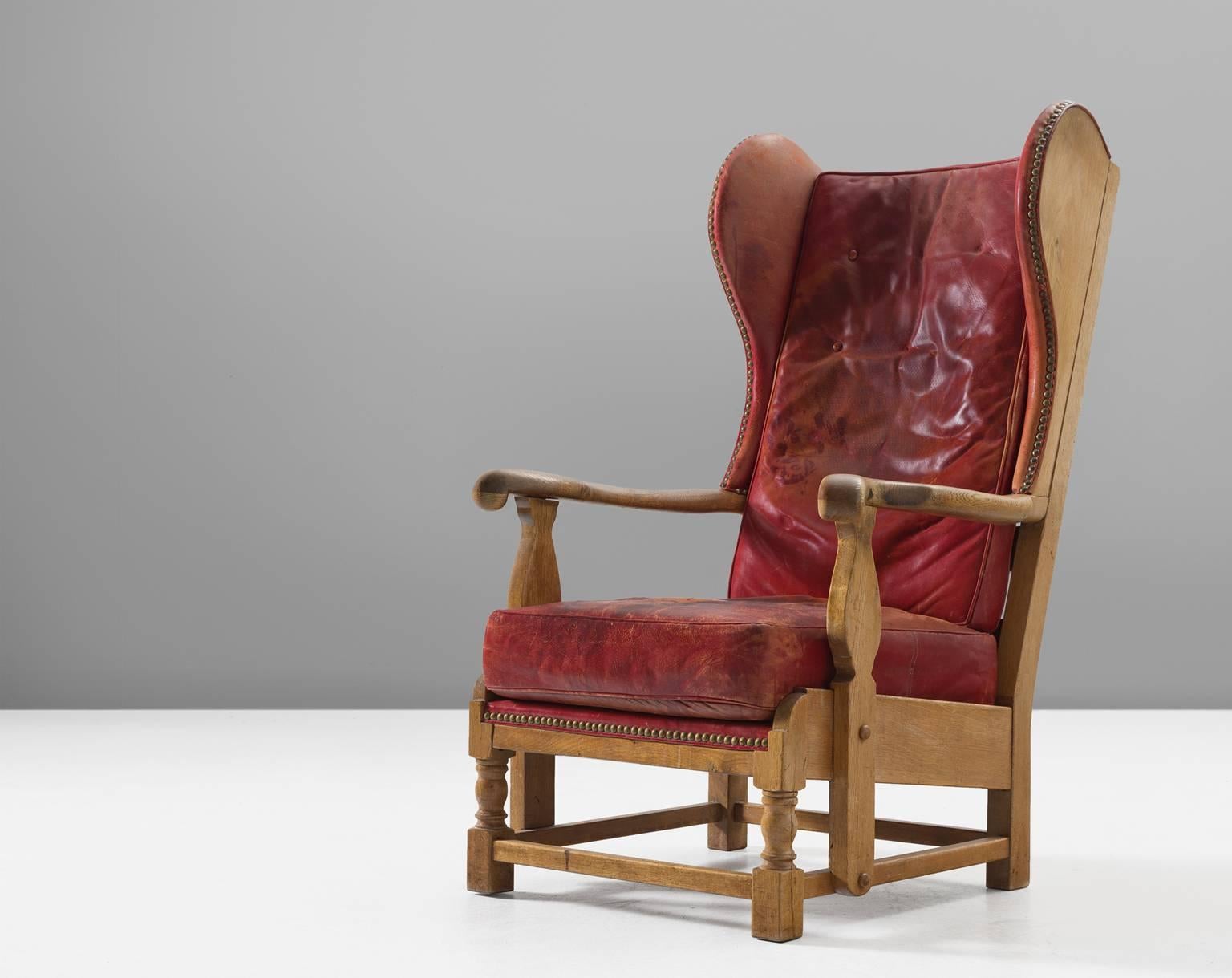 Lounge chair, red leather and oak, Denmark, 1930s.

This very rare early Danish lounge chair has the traits of a wingback chair whilst at the same time breathing the atmosphere of a gone century. This chair is easily pictured in a country house. At