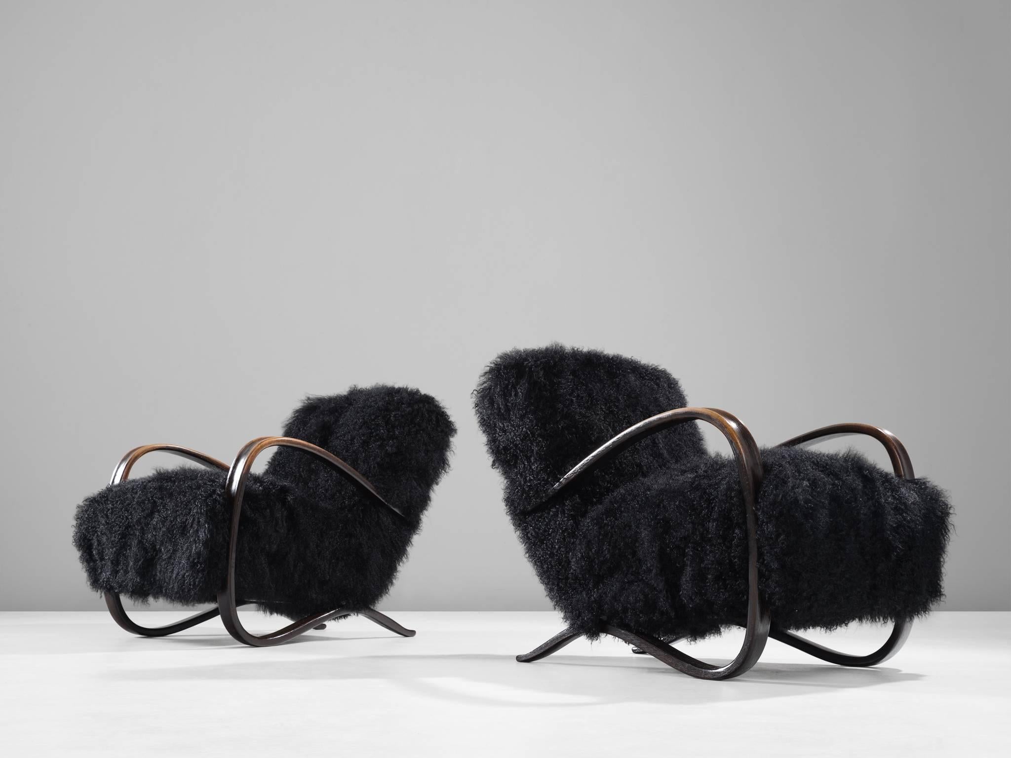 Pair of lounge chairs, in beech and sheepskin, by Jindrich Halabala, Czech Republic, 1930s. 

Extraordinary pair of easy chairs with black Tibetan lambswool upholstery. These chairs have a very dynamic appearance. This fuzzy upholstery gives these