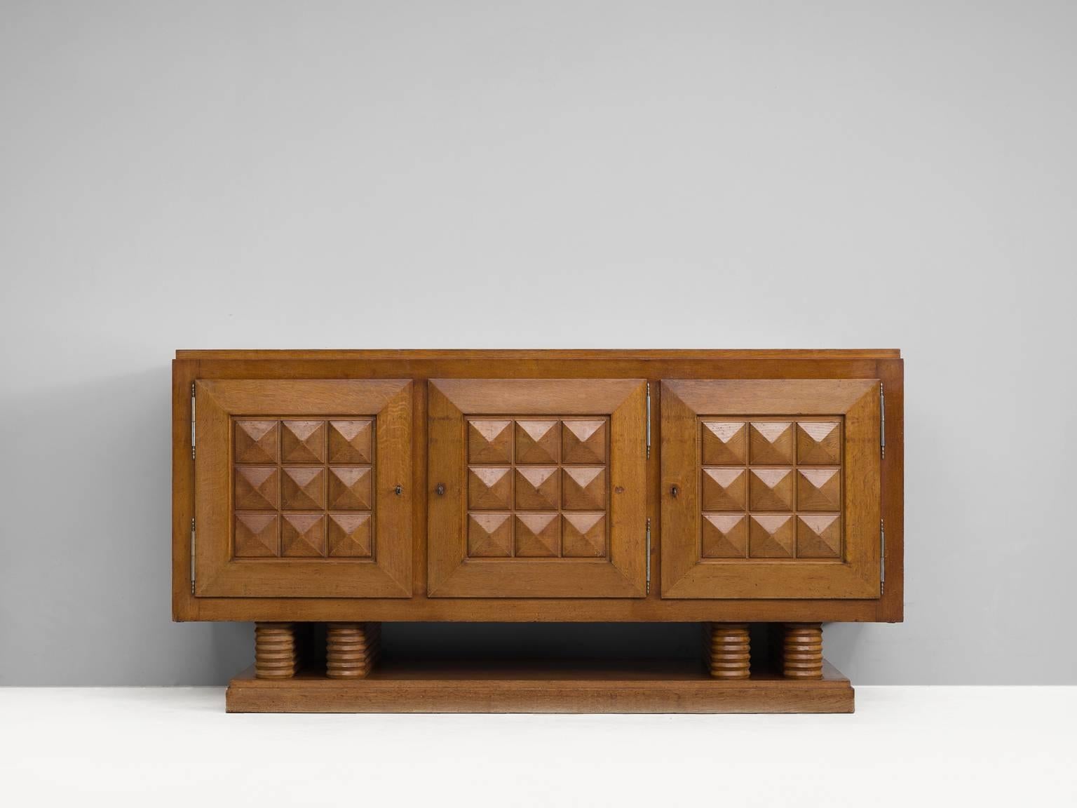 Sturdy Art Deco credenza in oak by Gaston Poisson, France, 1930s.

This three-door sideboard has well made graphical door panels and parquet top. The warm expression of the oakwood is wonderful, and shows a nice patina.

The piece is equipped