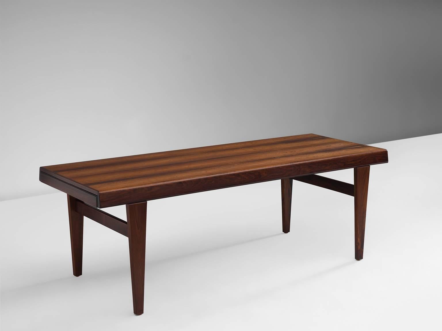 Bench, rosewood, Denmark, 1950s.

This small wooden bench features tapered legs and horizontal slats that connect the legs on both ends. The end of the bench slightly protrudes on either side. The grain of the rosewood give this bench a warm and