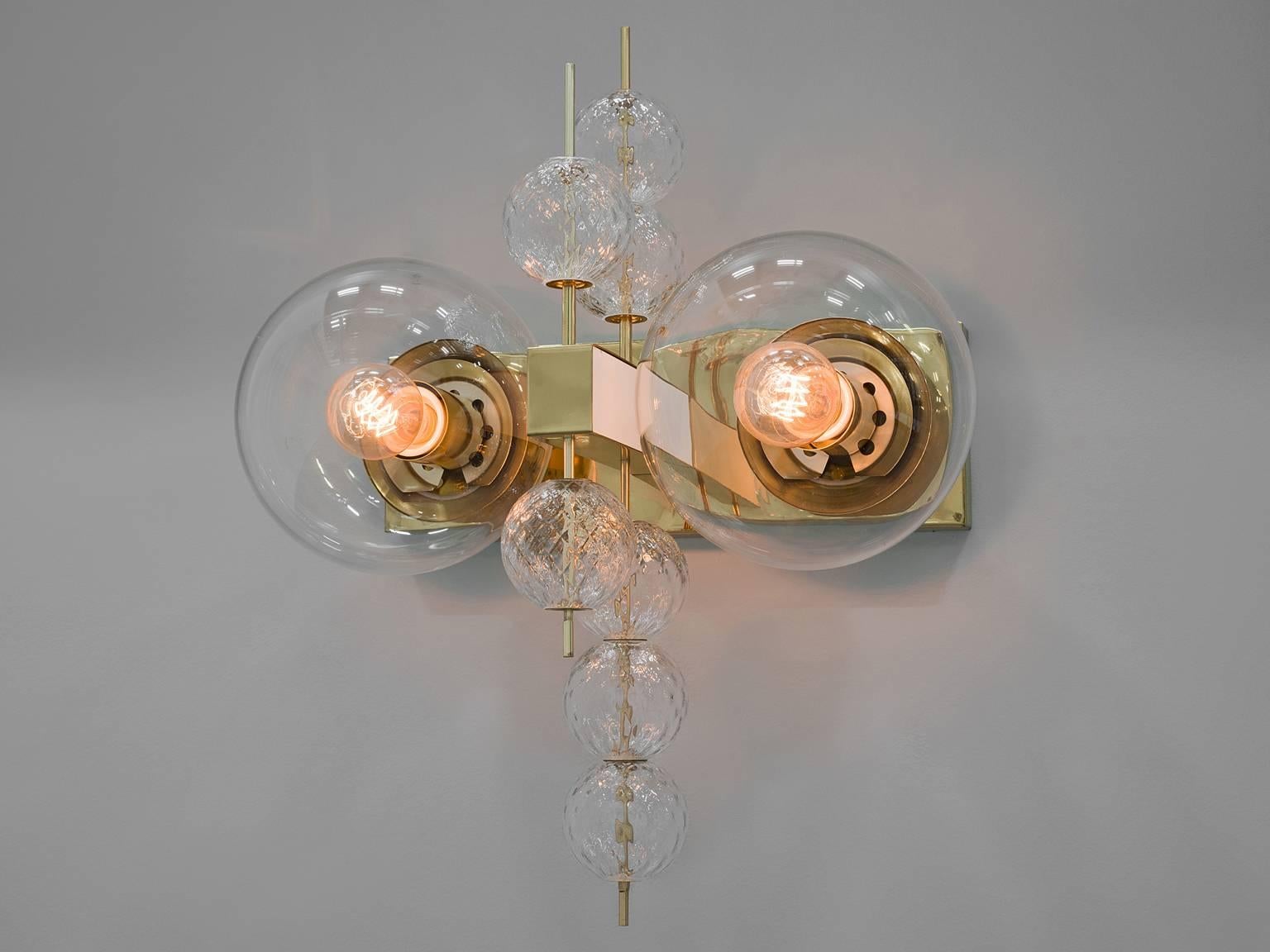 Chandelier in glass and brass, Europe, 1970s.

Ornate brass and glass wall light with two light points and small decorative structured glass globes. The chandelier is beautifully decorated thanks to the structured glass. The clear glass shades bring