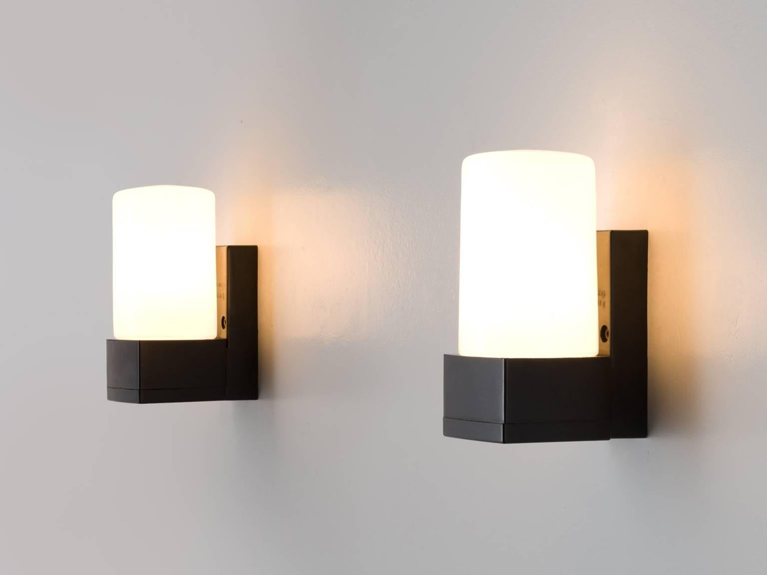 Wall lights, with black frame and opaline light, Europe, 1970s.

This set of wall lights is Minimalist and black and white cylinders. The cylinder is attached with a rectangular block to the wall and holds the opaline cone. The light partition is