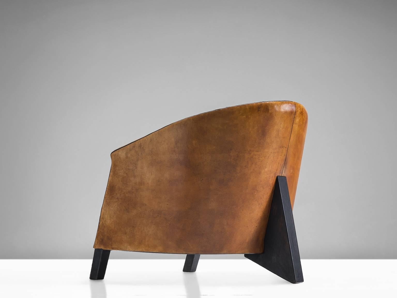 Cognac club chair, in leather and wood, Europe, 1970s.

This club chair in cognac leather with black piping has a very original and strong appearance. The sturdy design has an interesting playful base that provide the model with a certain lightness.