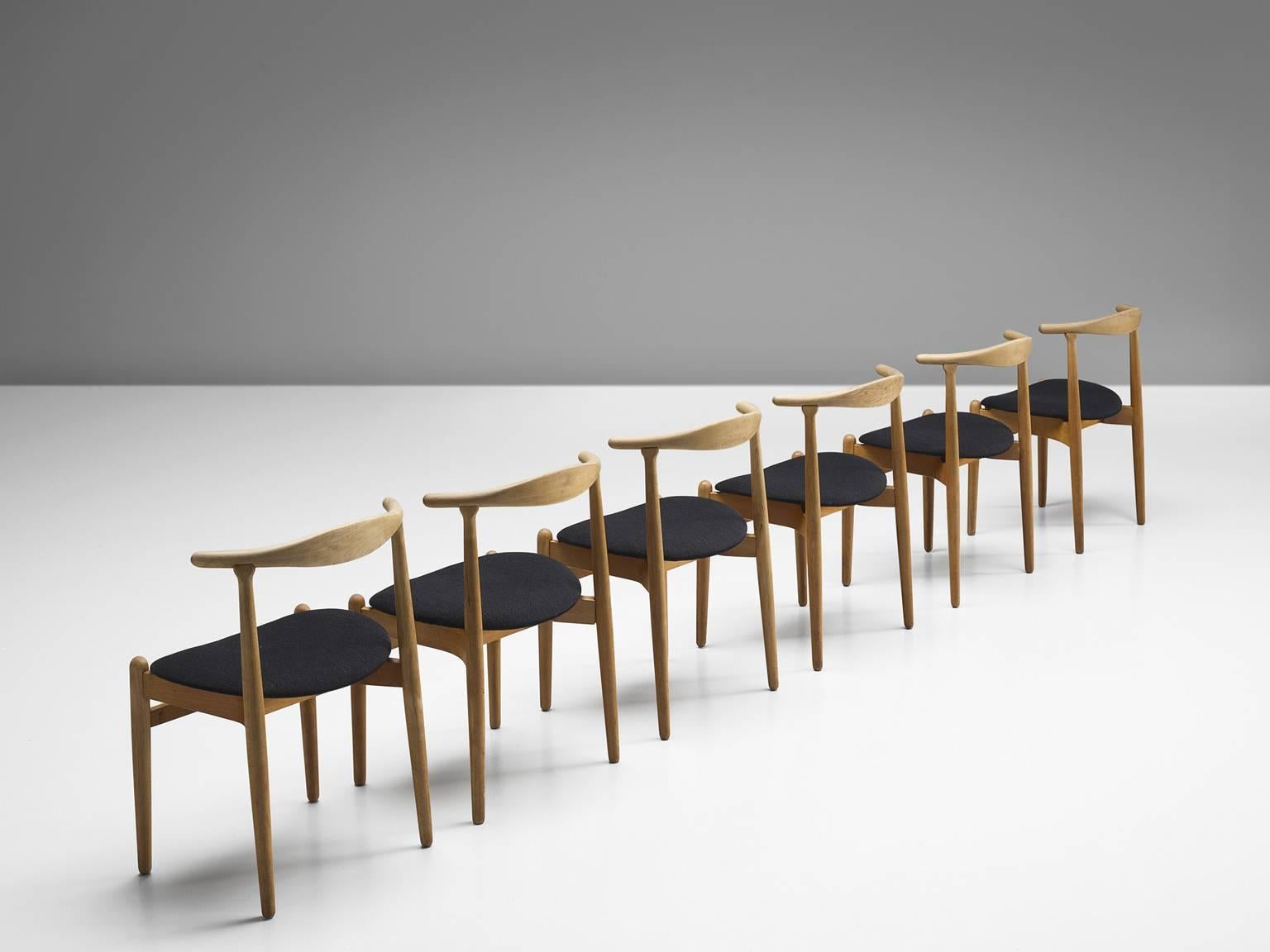 Dining chairs, oak and fabric, Denmark, 1960s.

These small elegant dining chairs feature a solid wooden curved backrest. There are four straight legs and the two front legs are connected via a horizontal slat. The legs slightly protrude above the