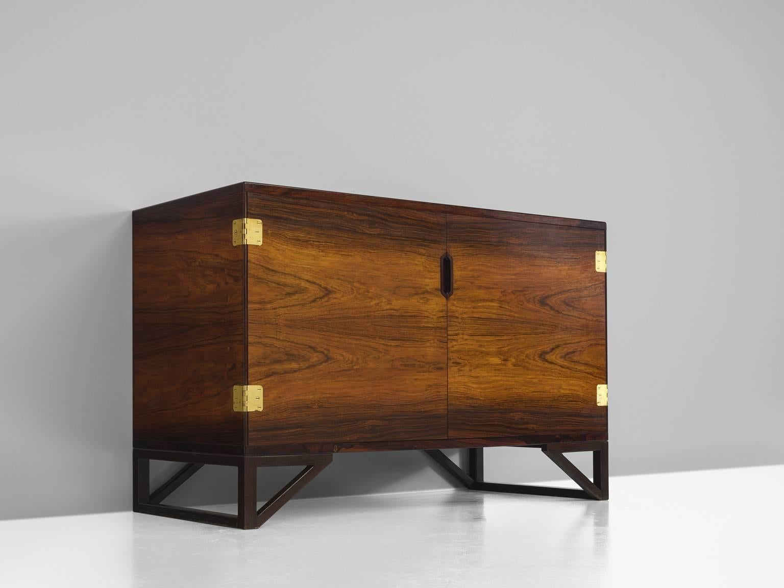 Cabinet, in rosewood and brass, by Svend Langkilde for Illums Bolighus, Denmark, 1950s. 

Modest and refined rosewood cabinet designed by Svend Langkilde, produced by Illums Bolighus. This sideboard is equipped with Langekilde's signature graphic