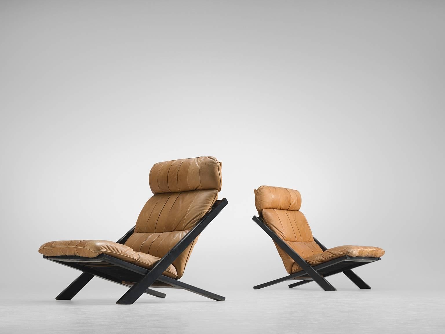 Pair of lounge chairs, in wood and leather by Ueli bergere for De Sede, Switzerland, 1970s.

High back lounge chairs by de Swiss quality manufacturer De Sede. The X-shaped frame consists of black lacquered wood. This makes an interesting contrast to