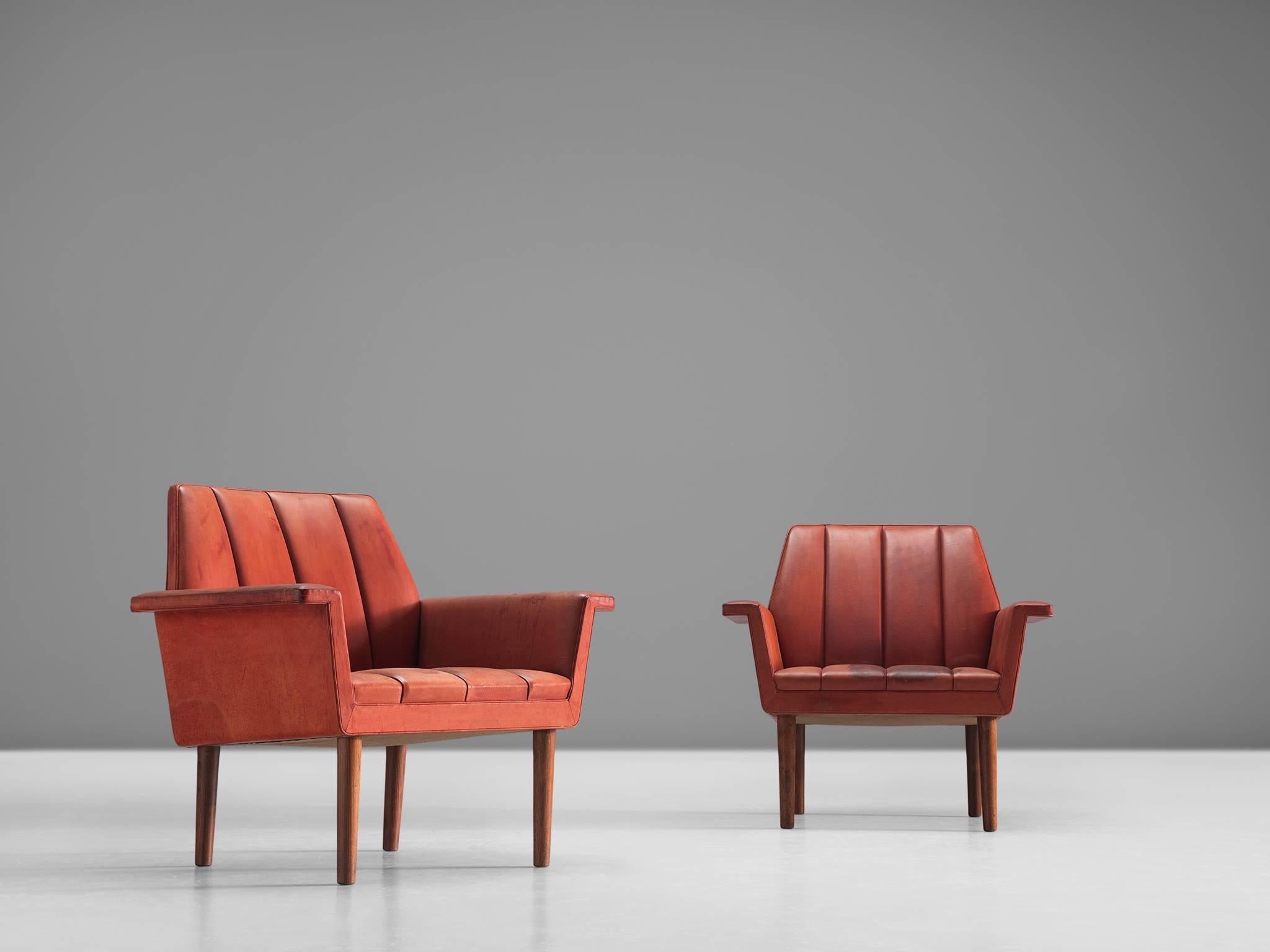 Set of two armchairs, in red leather and wood by Helge Vestergaard-Jensen for Peder Pedersen, Denmark, 1960. 

Pair of red leather armchairs that stand high on their wooden legs, these chairs have a stately appearance. The seating is simplistic with