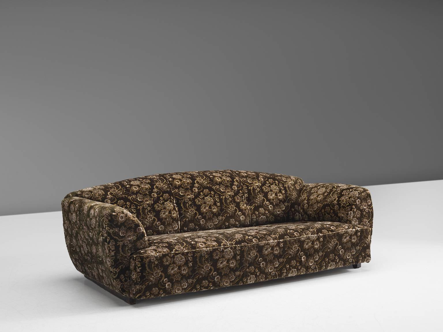 Settee, brown floral fabric, foam, wood, Scandinavia, 1950s.

This voluptuous sofa is a true delight to sit in. The thick, luxurious cushions on armrests, seat and back support the sitter exquisitely. The design of the sofa is grand, bulky and