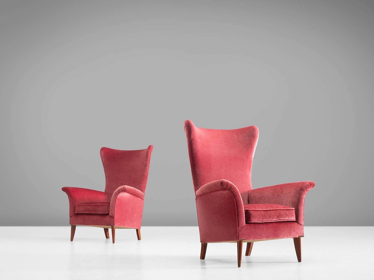 Set of two high wingback chairs, velvet and wood, Italy, 1950s. 

Pair of elegant Italian pink to vermillion red wingback lounge chairs. Beautiful organic formed seating, with solid wooden legs. The gentle flared armrests and seating give this