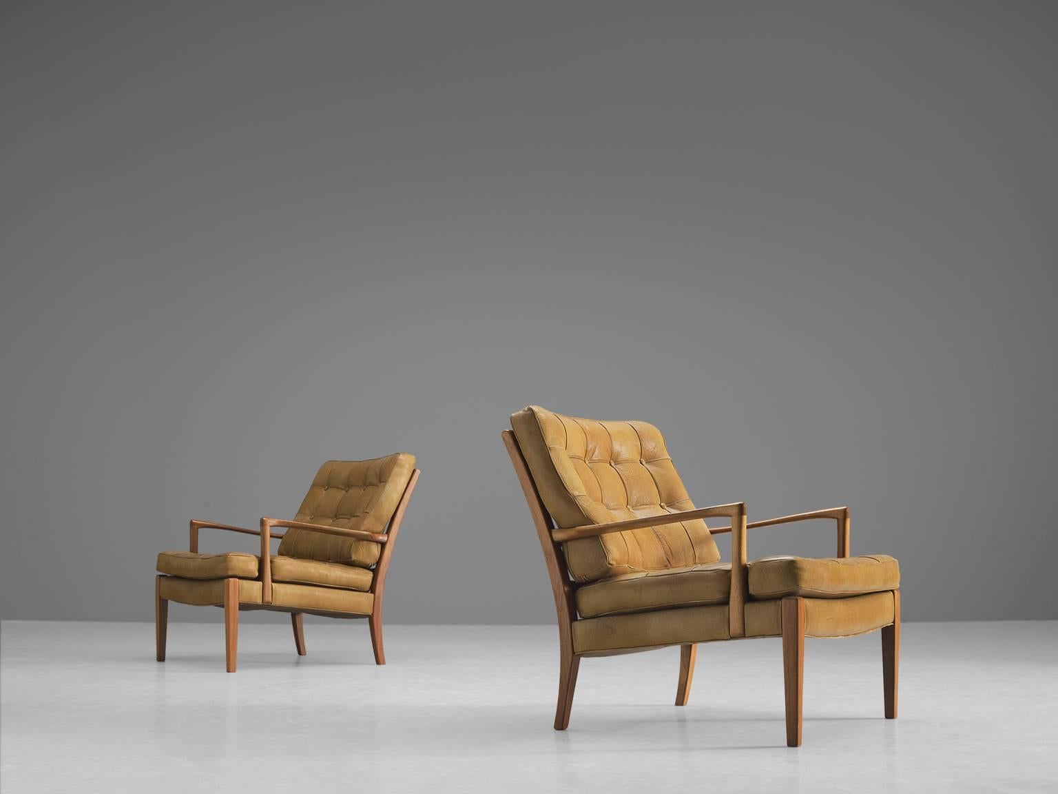 Two easy chairs, in brown, cognac leather and teak, by Arne Norell, Sweden, 1960s. 

Elegant armchairs with quilted light camel brown buffalo leather. The tufted cushions show a stunning patina, which gives these chairs a vibrant appearance. The