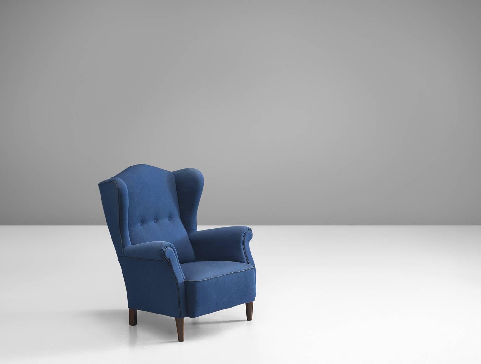 Easy chair, blue fabric, piping, stained beech legs, Denmark, 1940s. 

This Danish wingback chair is upholstered with the original fabric. The stately chair, which originates from the 1940s is the predecessor of what came to be known as modern