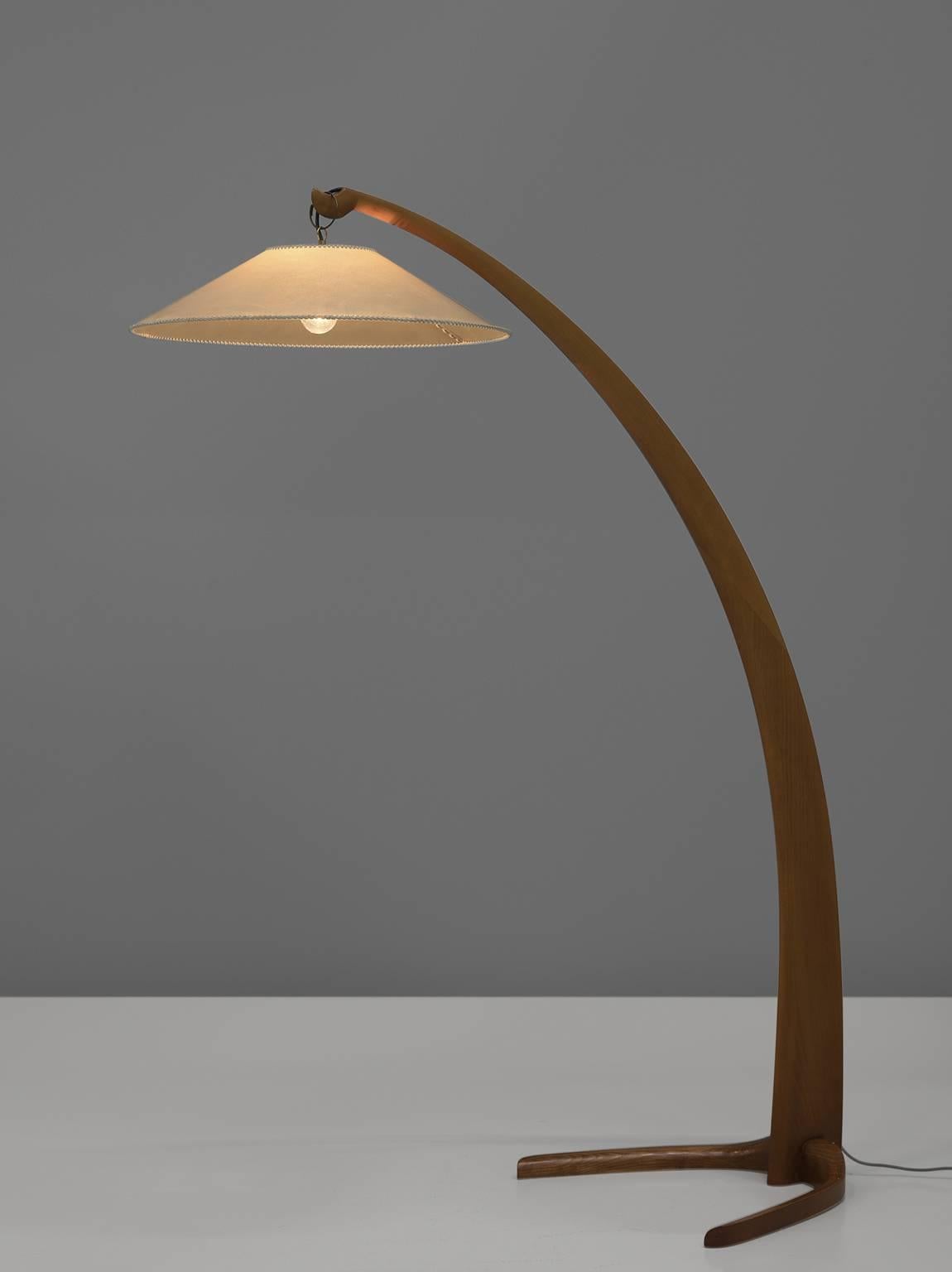 Floor lamp, wood, canvas, Italy, 1950s. 

This early floor lamp features a sculptural wooden base with a slender, long shaft that tapers towards the top and stands on two feet. From the shaft a bended shade faces downwards. Very elegant and