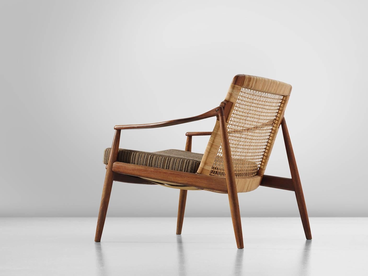 Armchair, teak and rattan, Hartmut Lohmeyer, manufactured by Wilkhahn, teak, cane, striped brown beige upholstery, Germany, design 1956, production 1960s.

This low reclining armchair is sensuous and is organically shaped. They feature a slightly