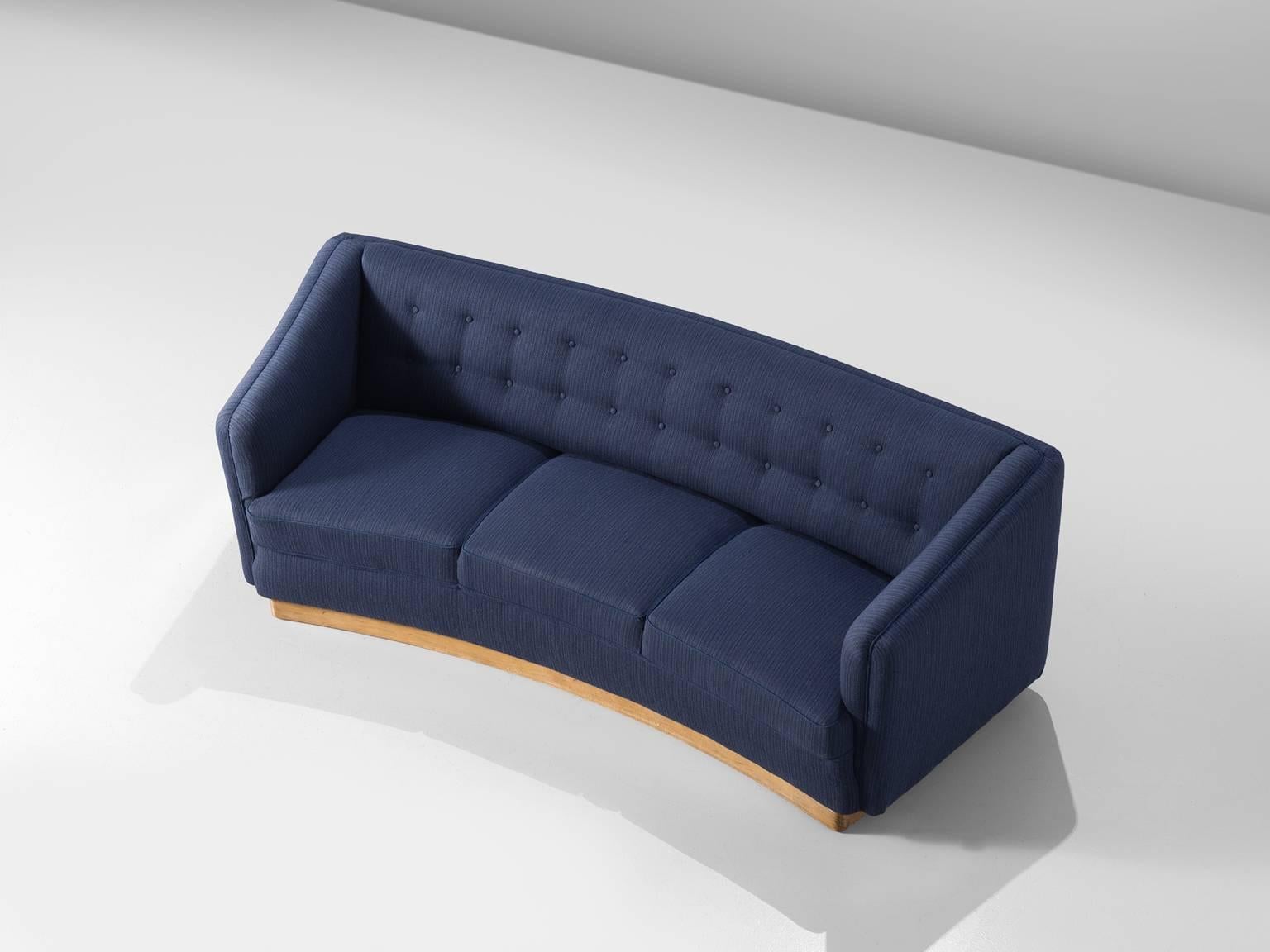 Three-seat sofa, navy blue upholstery, wooden base, 1960s, Denmark.

This curved three-seat sofa with a deep blue upholstery is finished with a slightly lighter tone piping. The sofa is slightly curved and has a padded back and unusually high