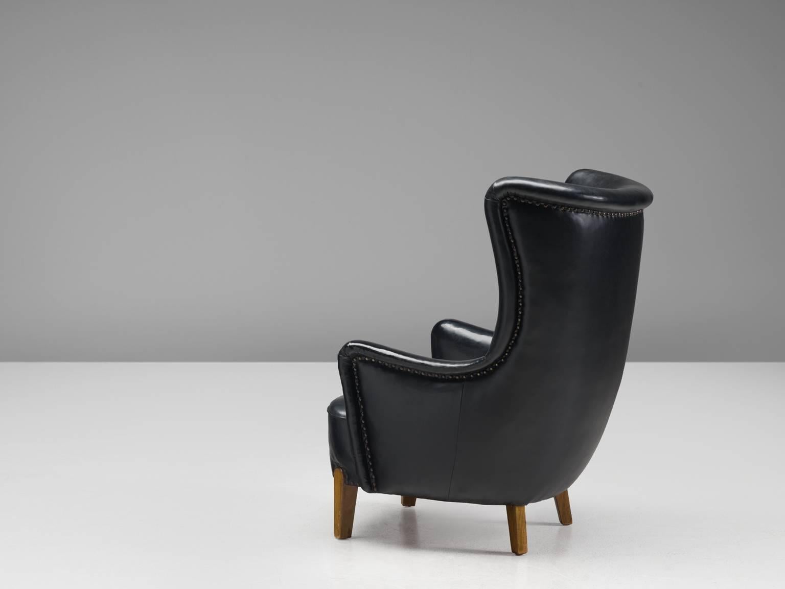 Easy chair, black faux leather and beech, Denmark, 1960s

This black leatherette chair is manufactured by a Danish cabinetmaker. The easy chair features legs of beech. The seat, sides and back are upholstered with black nail fitted vinyl that forms
