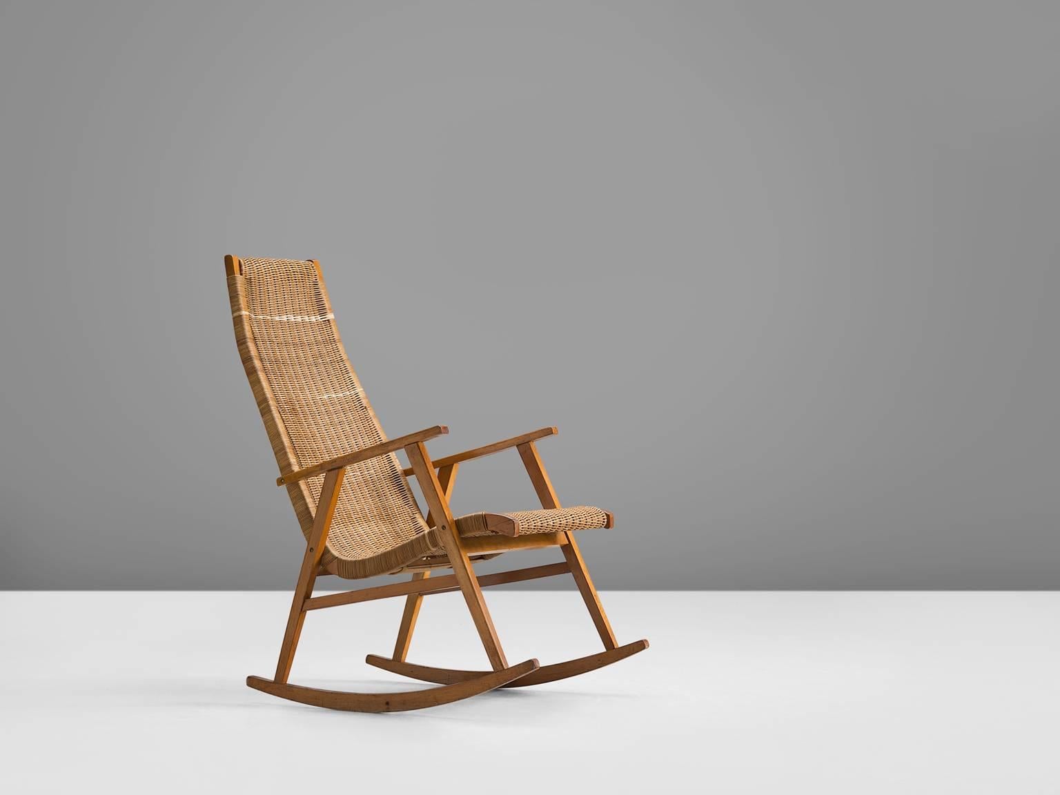 Lounge chair, in cane and wood, The Netherlands, 1950s. 

This Classic rocking Dutch rocking chair features a simplistic, functional frame. The back of the chair however is unusually long giving this comfortable chair a certain grandeur and