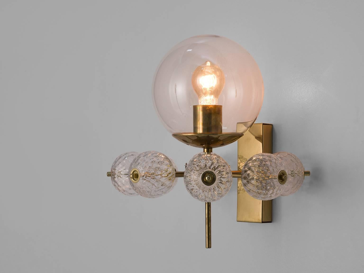 Wall chandelier in glass and brass, Europe, 1970s.

Ornate brass and glass wall light with one light points and a circle of structured, decorative glass globes underneath. The scone is beautifully decorated thanks to the structured glass. It shows a