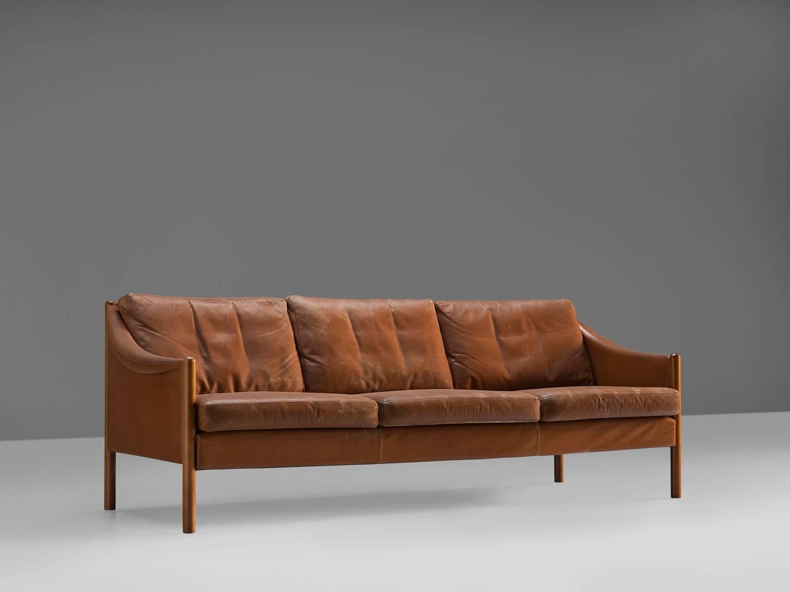 Settee, in leather and wood, Denmark, 1963.

Sofa with an elegant design in the style of Børge Mogensen. This sofa has a low, curved back, which smoothly runs over into the armrests with detailed piping. Seating and back feature dawn filled